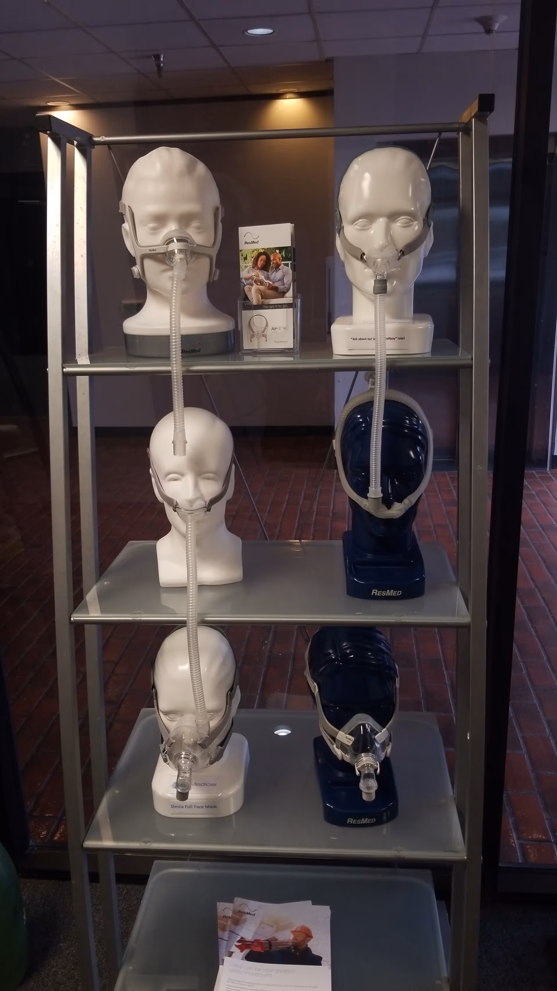Medical equipment display with CPAP masks and mannequin heads on metal shelves.