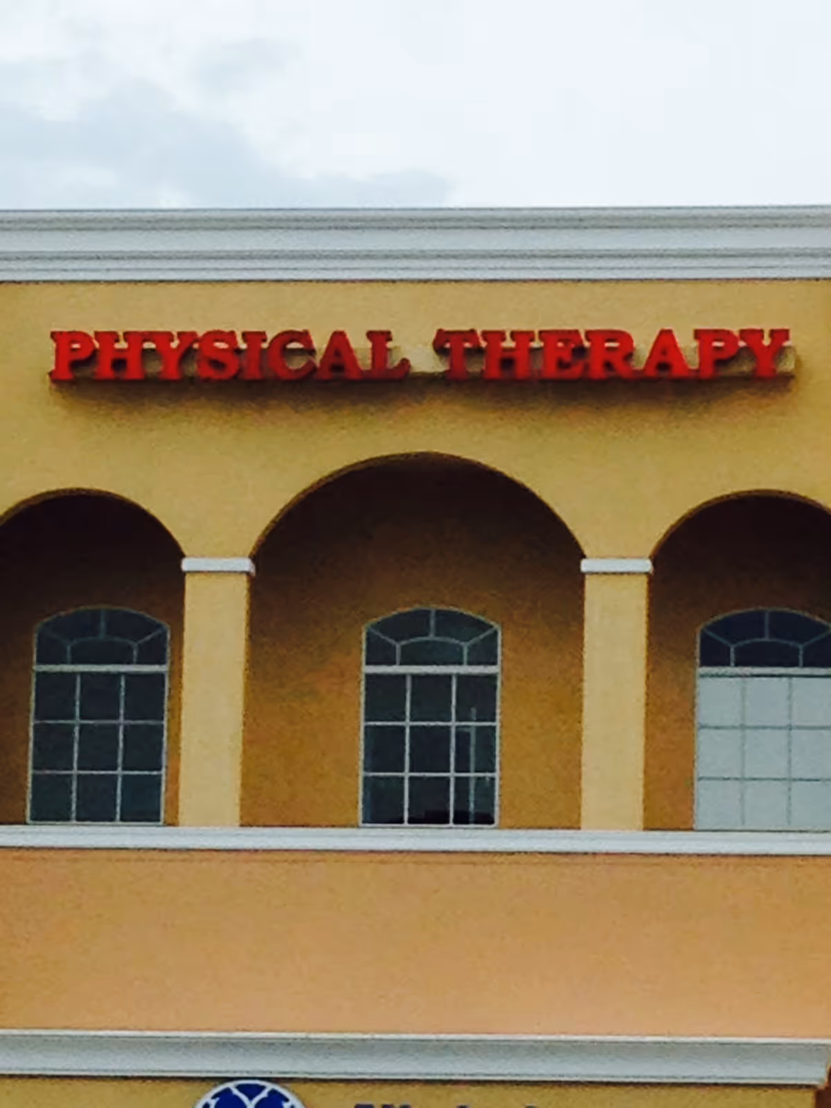 Front exterior of a yellow building with a Physical Therapy sign.