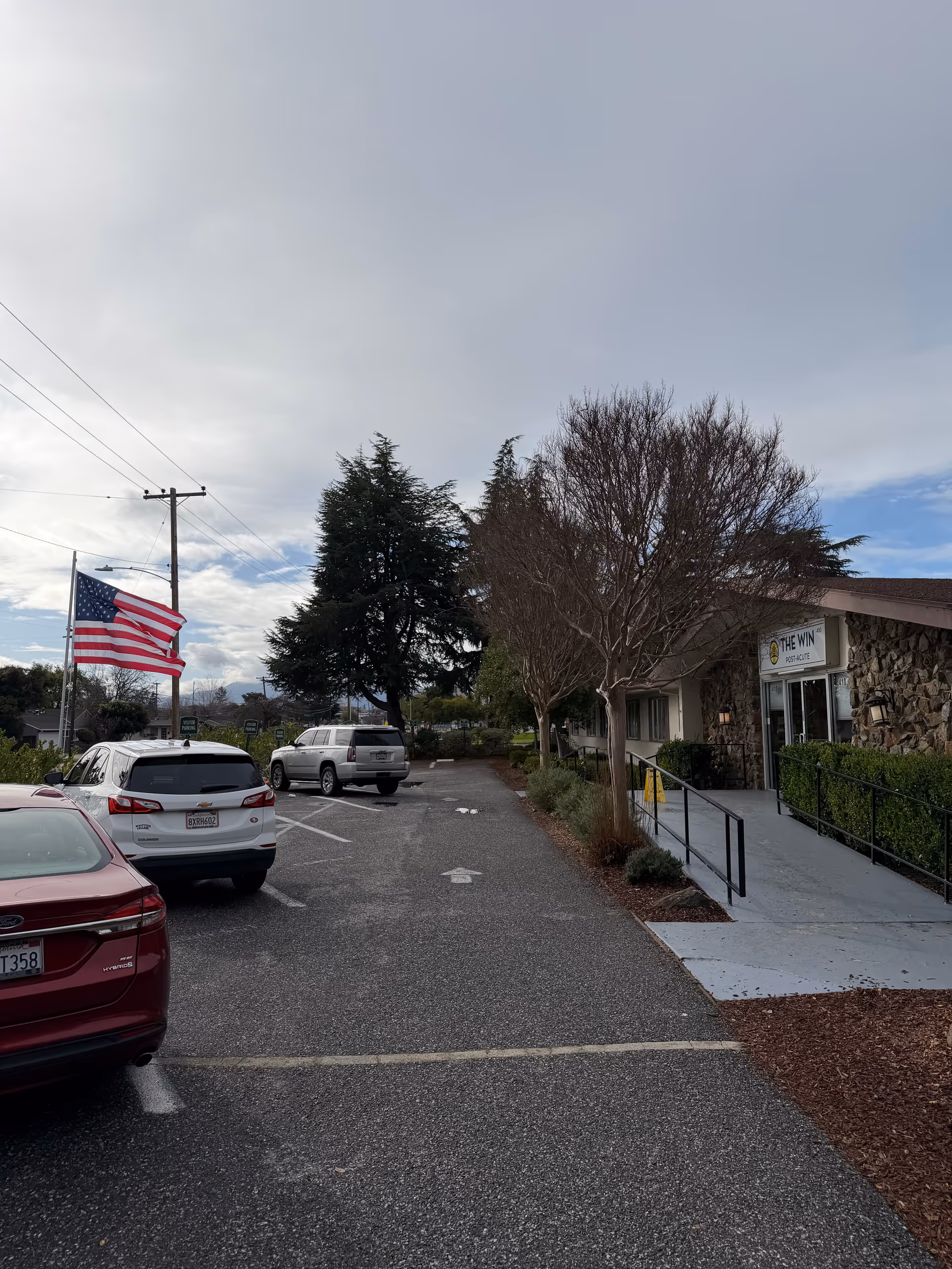 Exterior view of Mission Skilled Nursing & Subacute Center with parked cars and American flag.