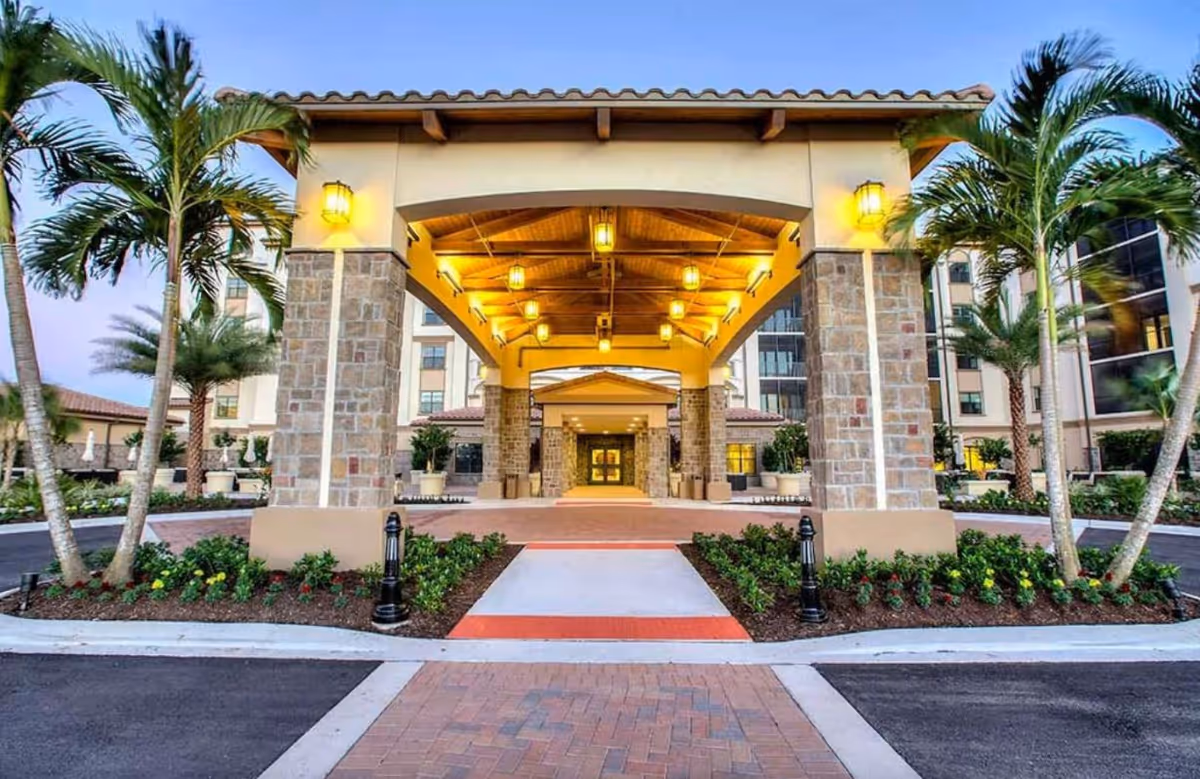 Front entrance of Stillwater Health Care with stone pillars and palm trees.
