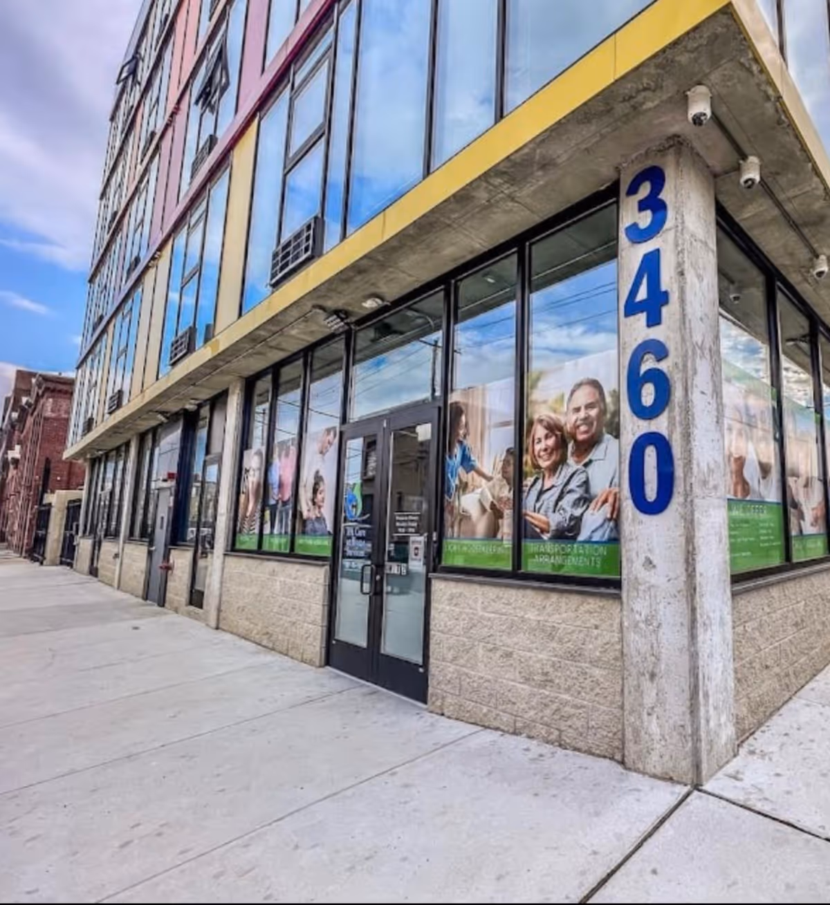 Exterior storefront with large glass windows, promotional posters, and a blue vertical address 3460.