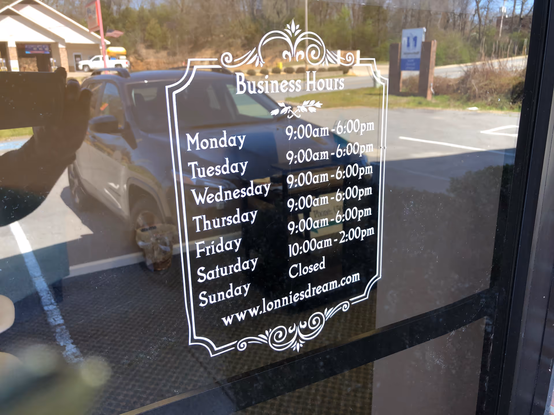 Glass door decal displays Lonnie's Dream In-Home Care business hours with parking lot reflection.