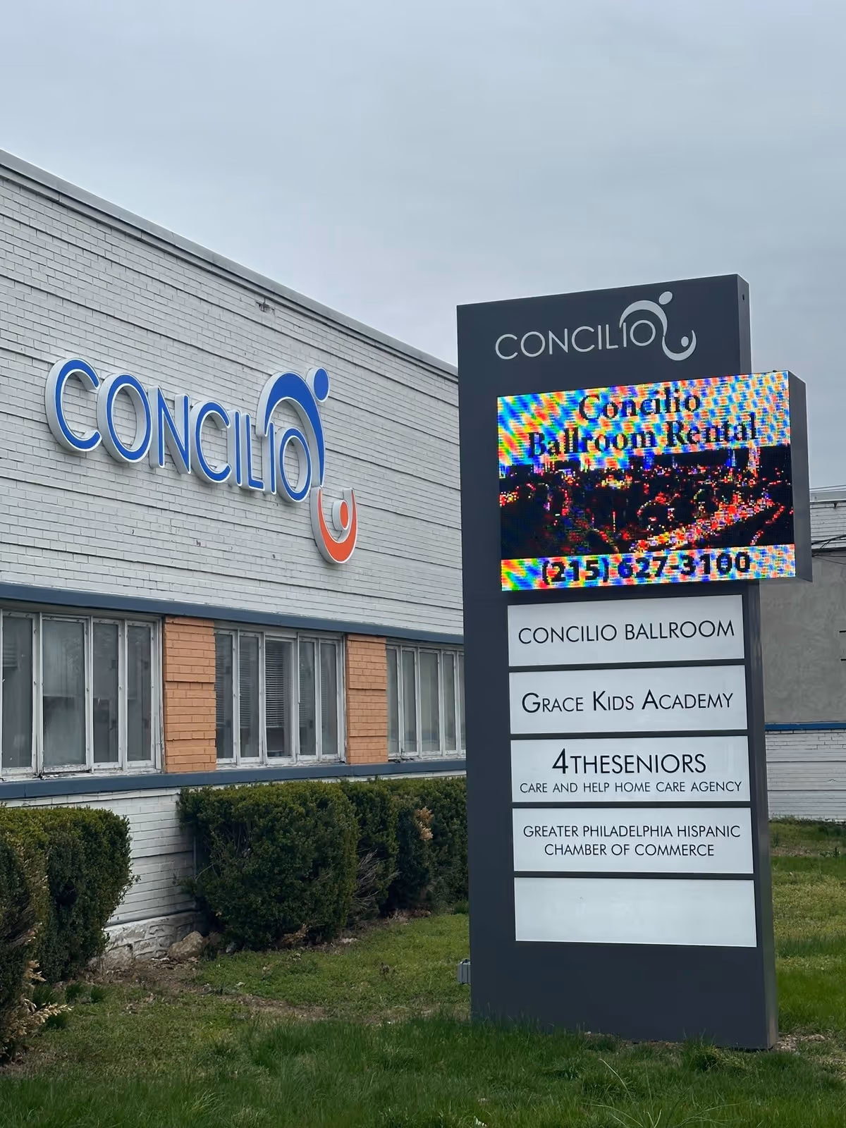 Exterior of a building with a large CONCILIO sign and a tall information sign.