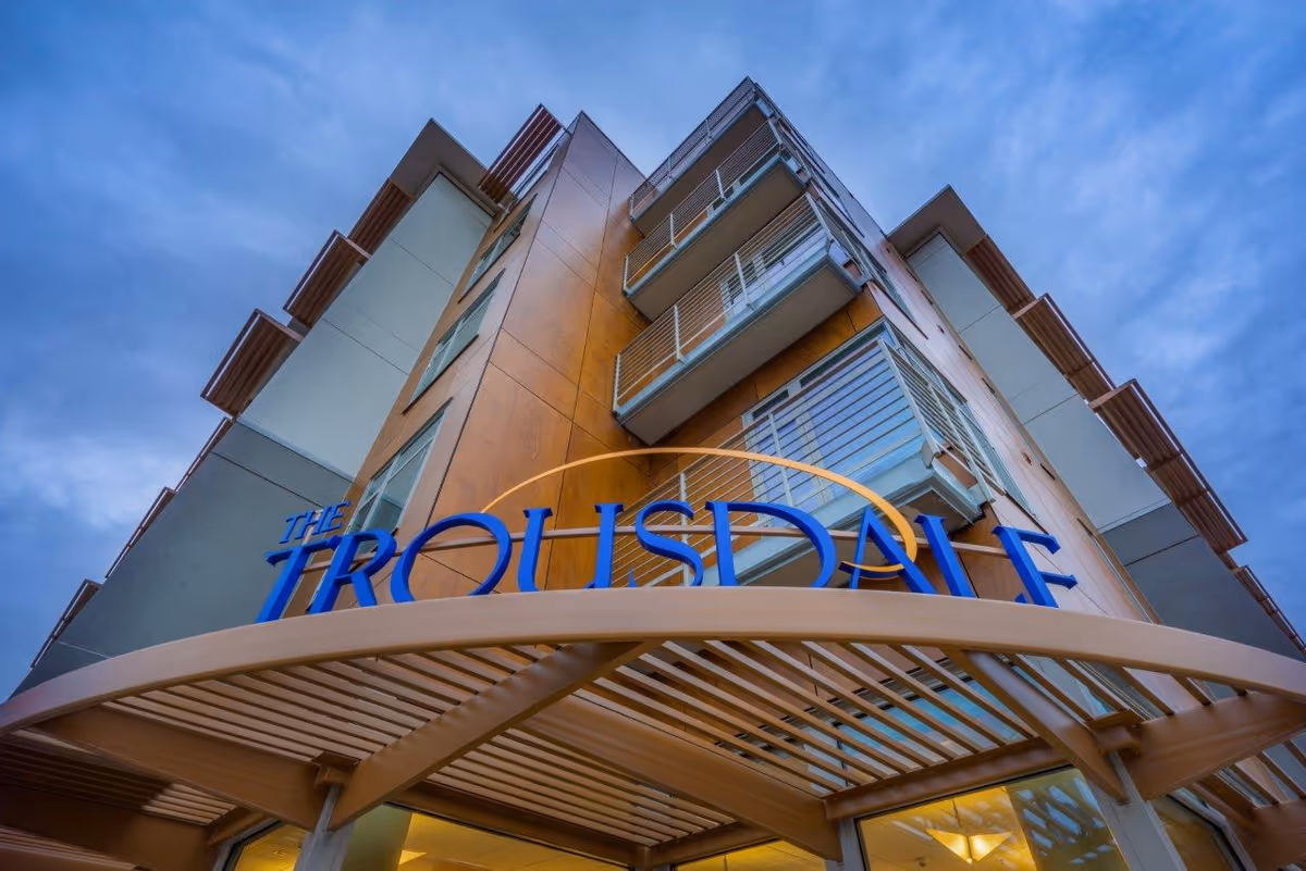 Exterior view of The Trousdale senior living building with blue sign.