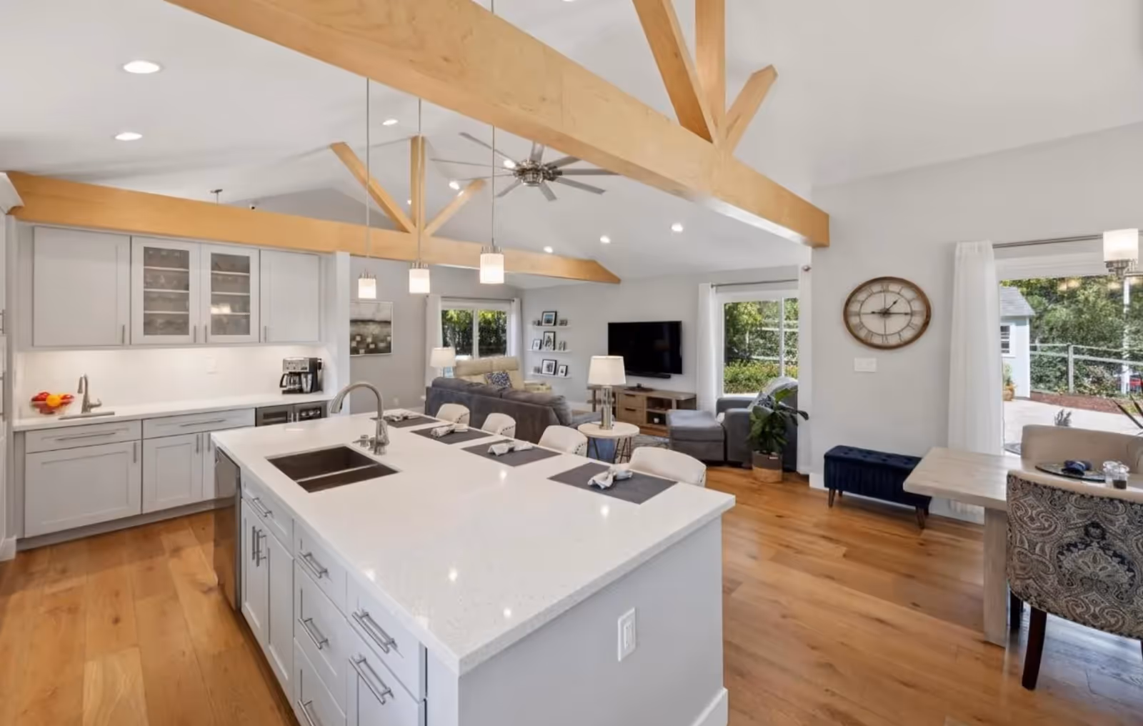 Open-concept kitchen and living area with an island, exposed wooden beams, and hardwood floors.