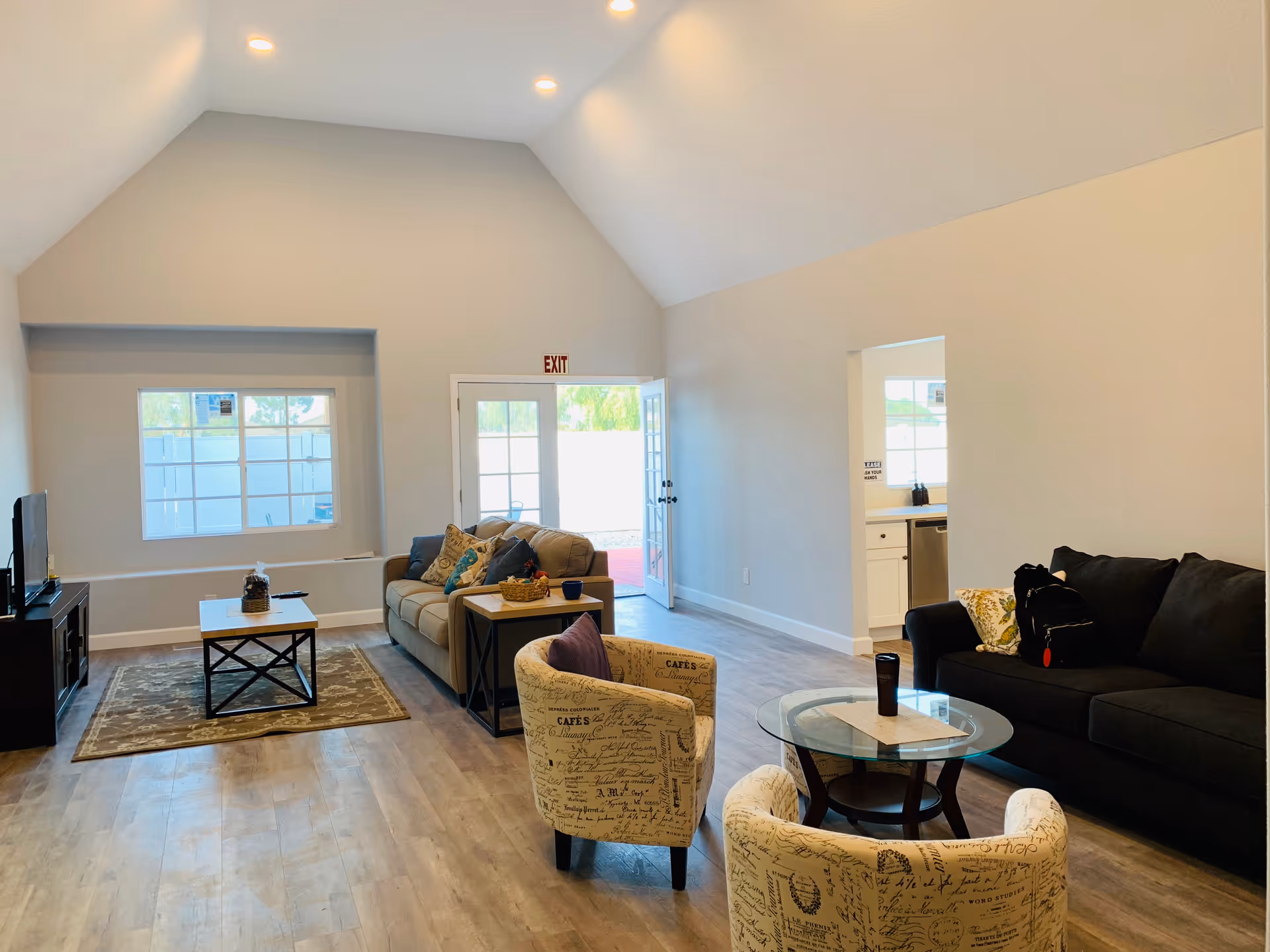 Bright open living room with sofas, chairs, coffee tables, and an exit doorway.