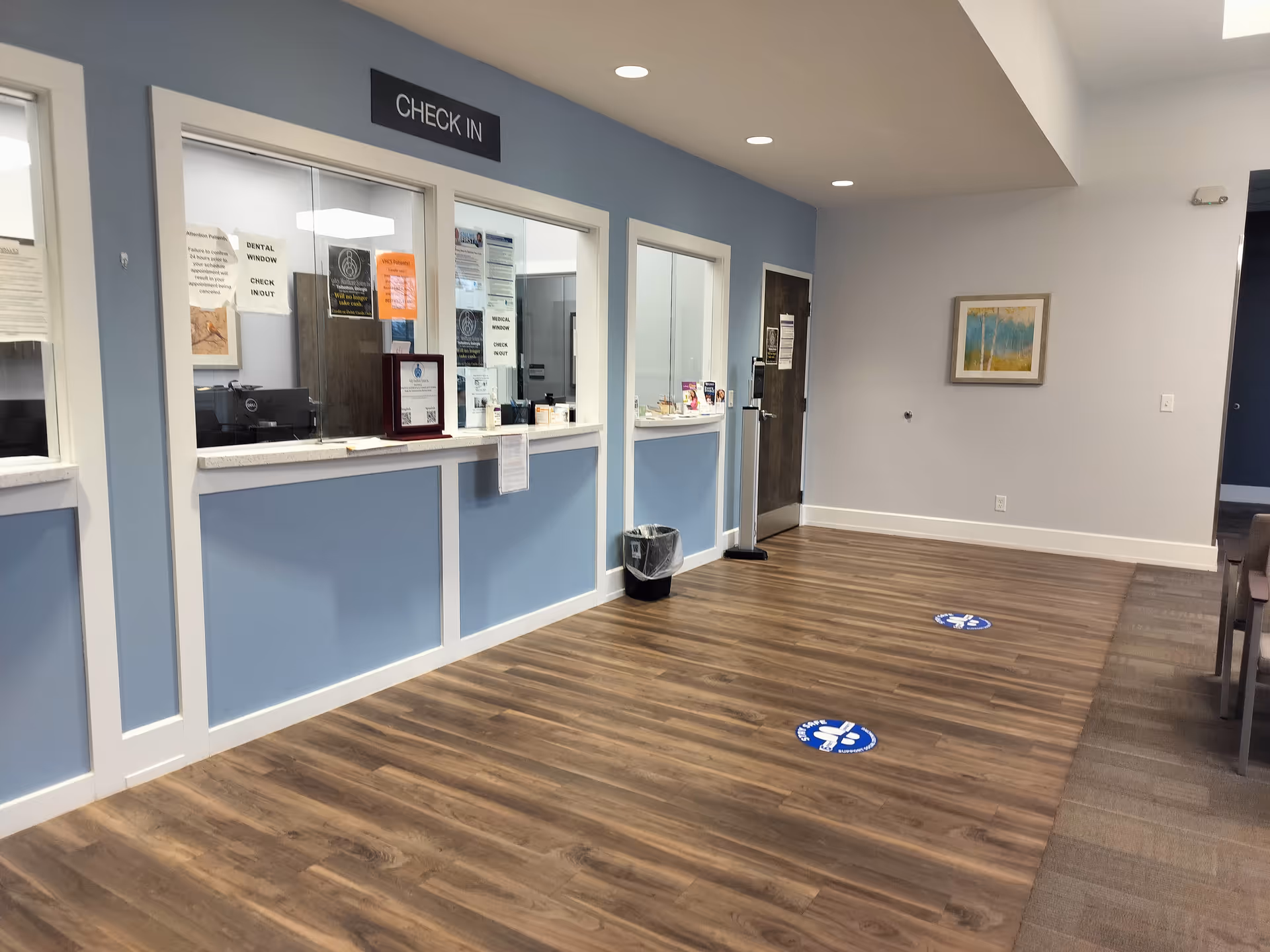Senior living facility check-in desk area with blue walls, windows, and wooden flooring.