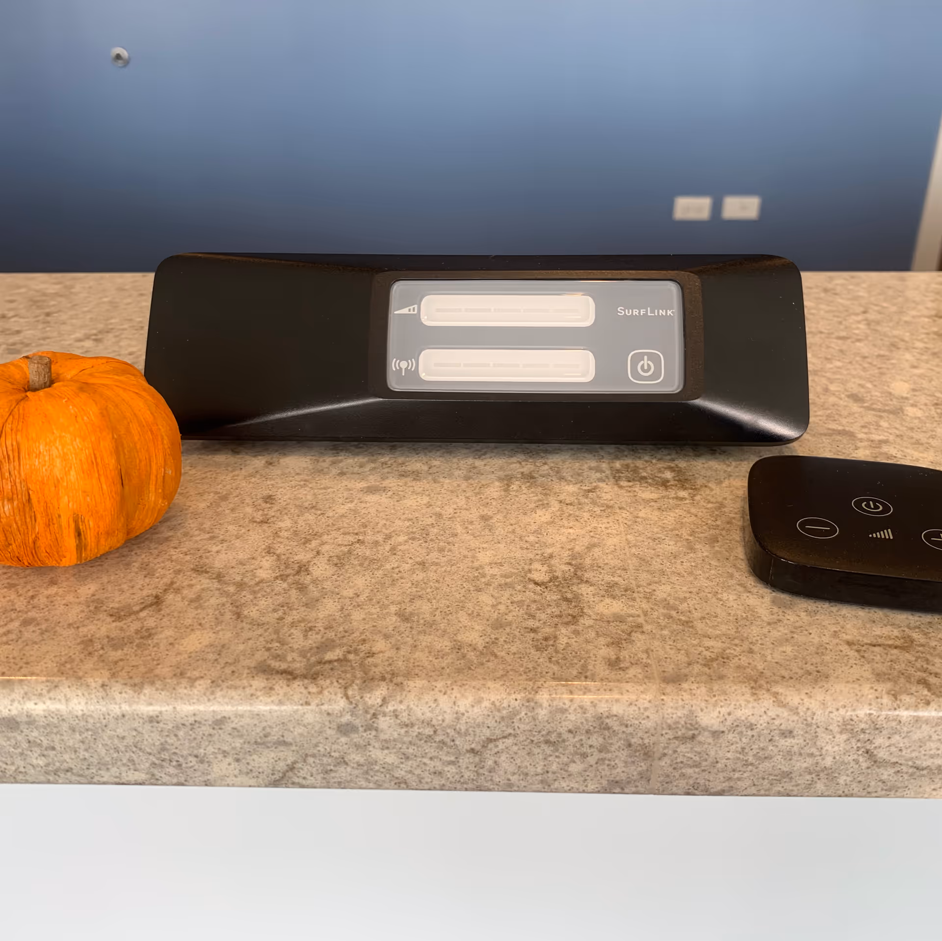 Countertop shows an orange pumpkin beside a SurfLink device and wireless remote