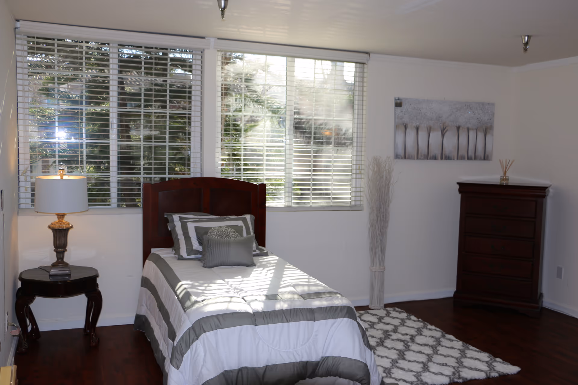 A neatly made bedroom in a Westgate Villa Assisted Living, featuring a single bed and dresser.