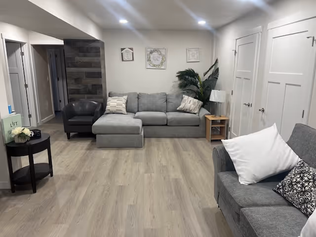 Cozy living room in a senior facility with gray couches and plants.