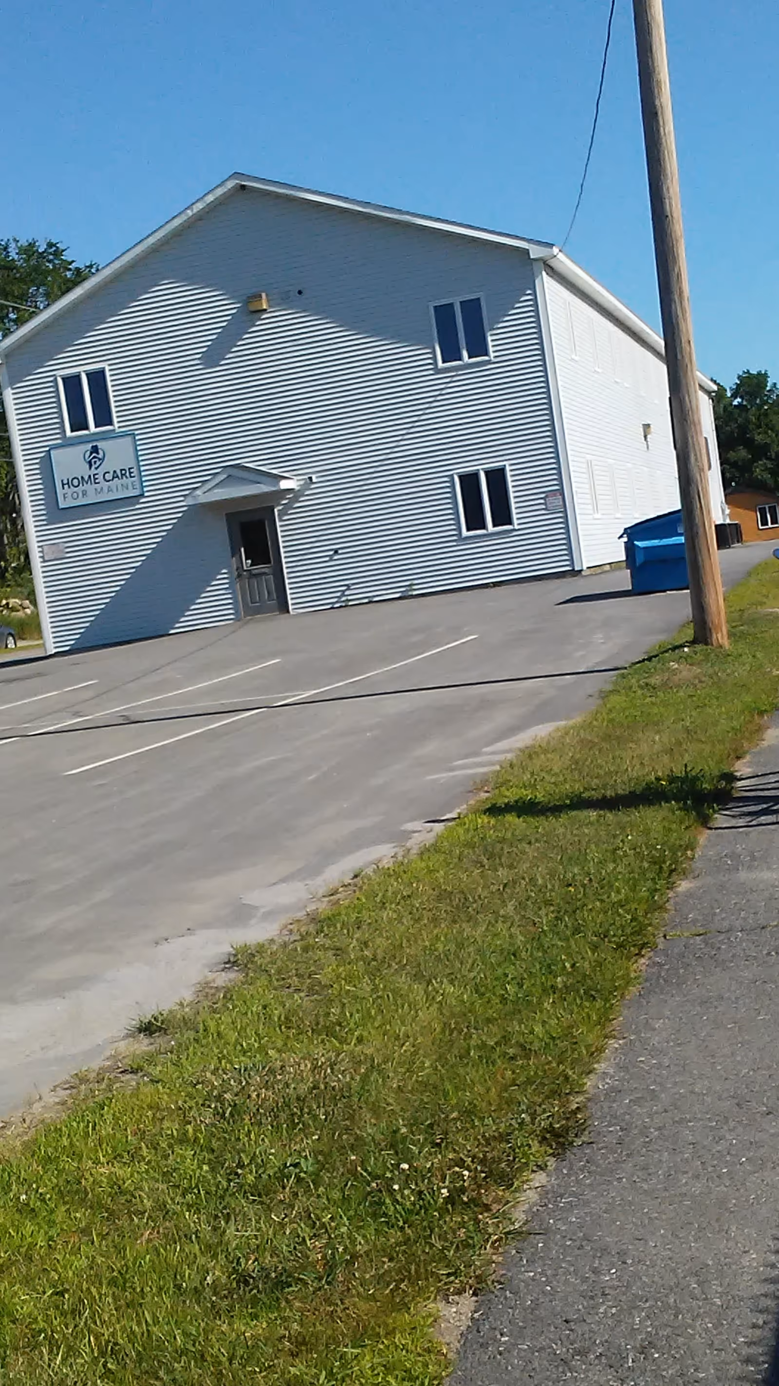 White two-story building with Home Care for Maine sign along a paved driveway