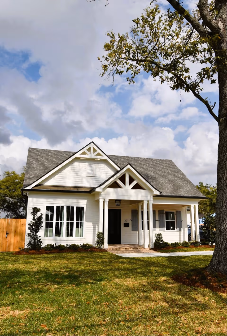 White, single-story senior living building with a pitched roof and front porch, surrounded by lawn