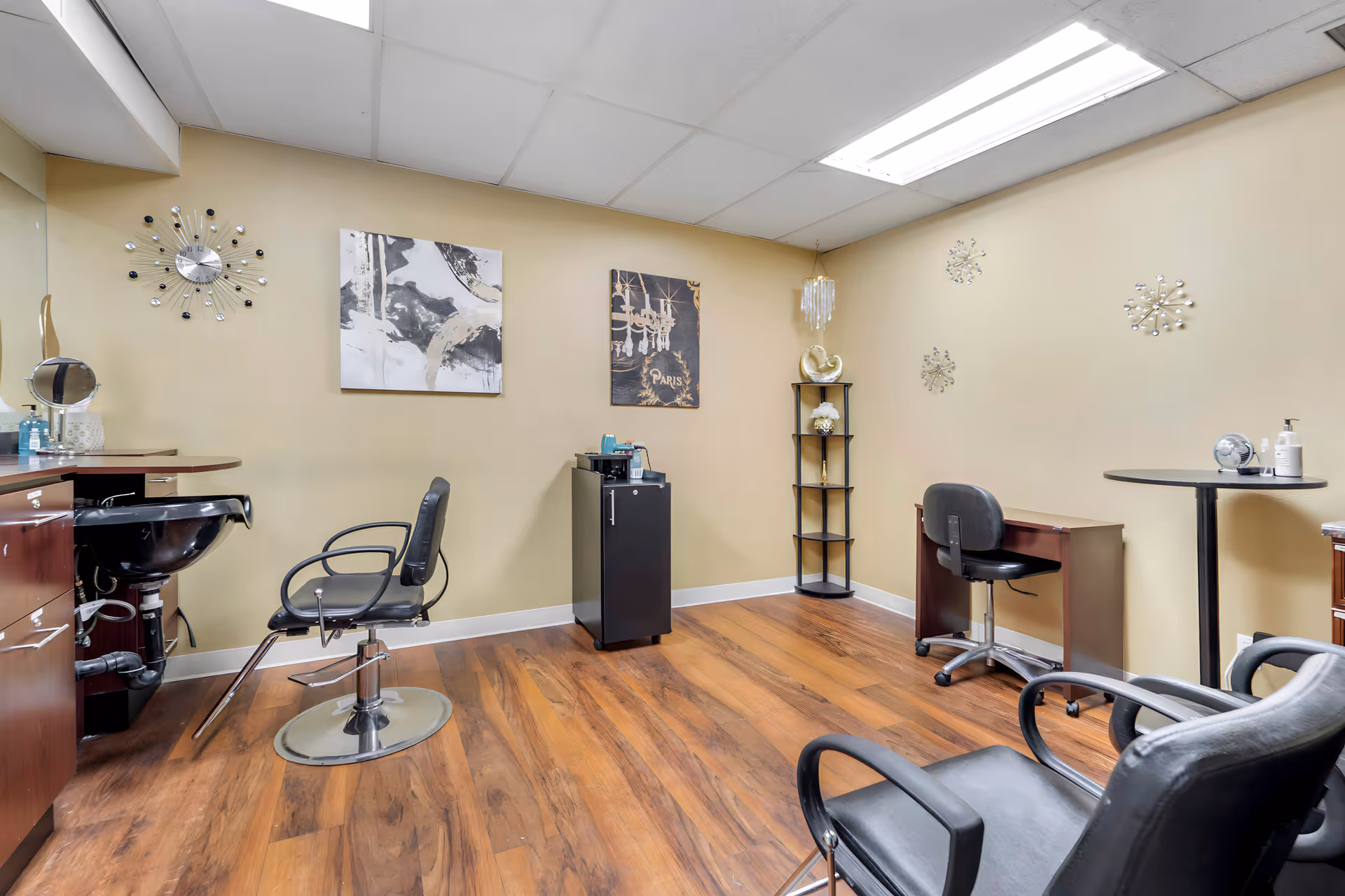 Interior salon area with styling chairs, sinks, and decorative wall art in a senior living facility.