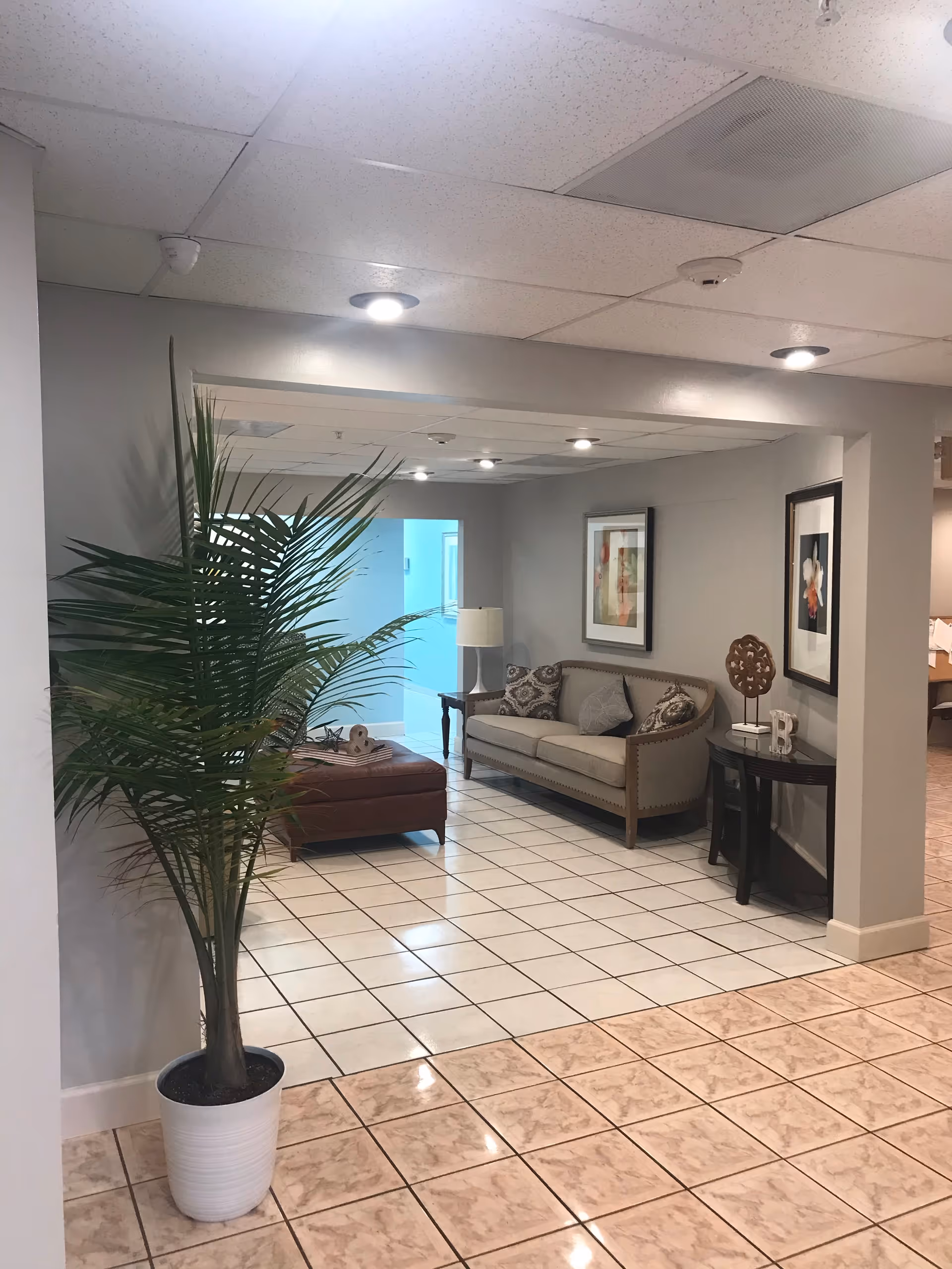 Lobby seating area with sofa, chairs, plant, and framed artwork.