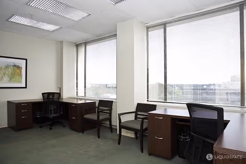 Office-like workspace with desks, chairs, and large windows in a senior living facility.
