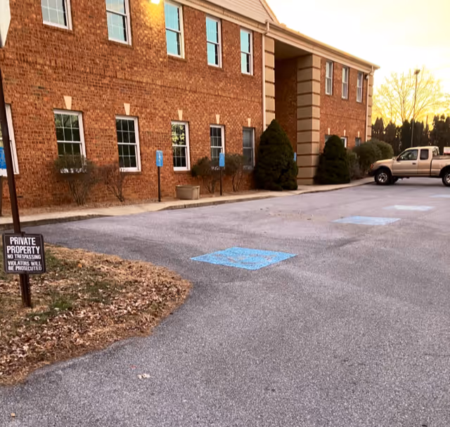 Brick senior living facility exterior with parking lot and blue handicapped spaces.