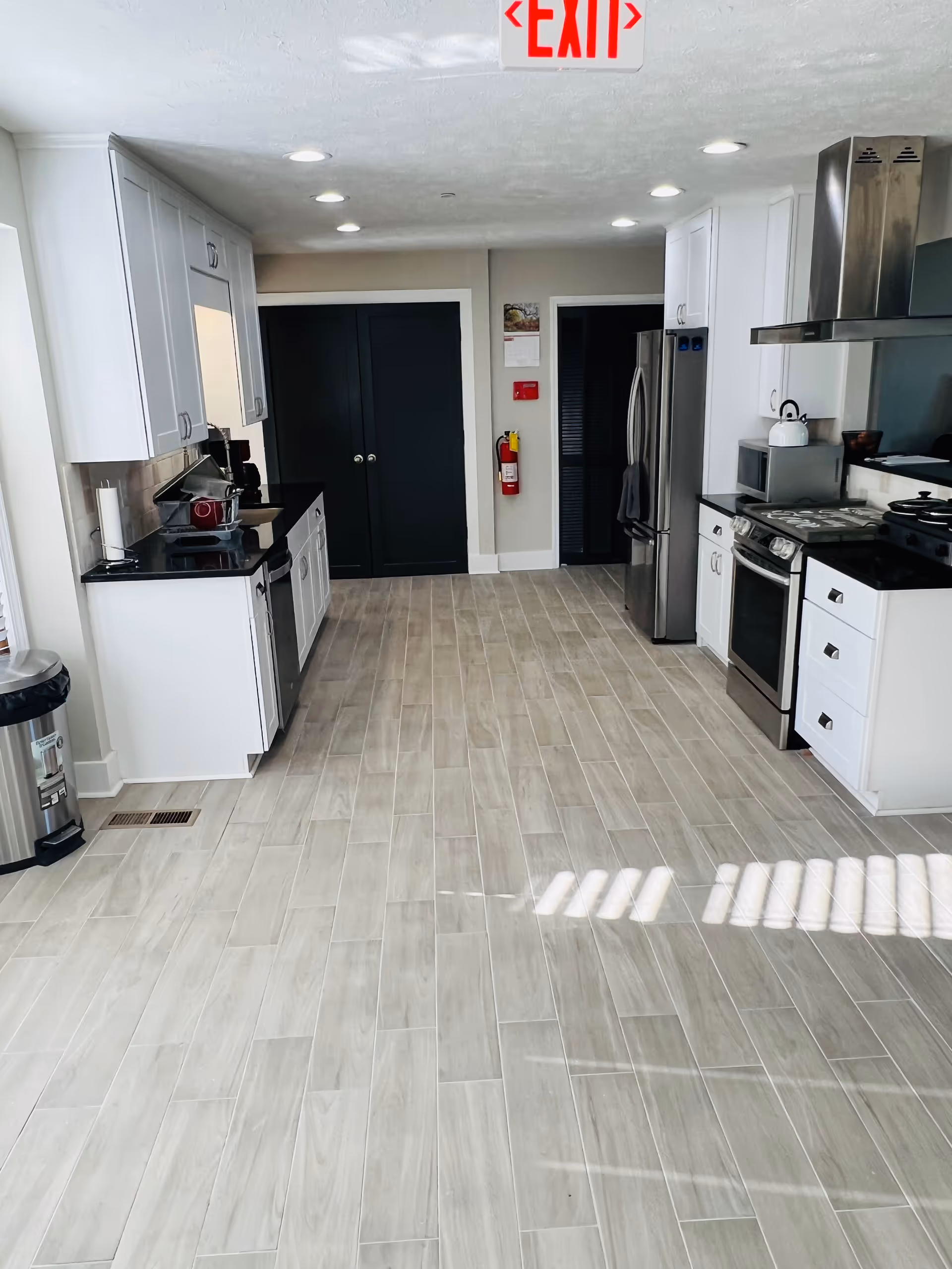 Bright modern kitchen with white cabinets, stainless steel appliances, and tiled floor.