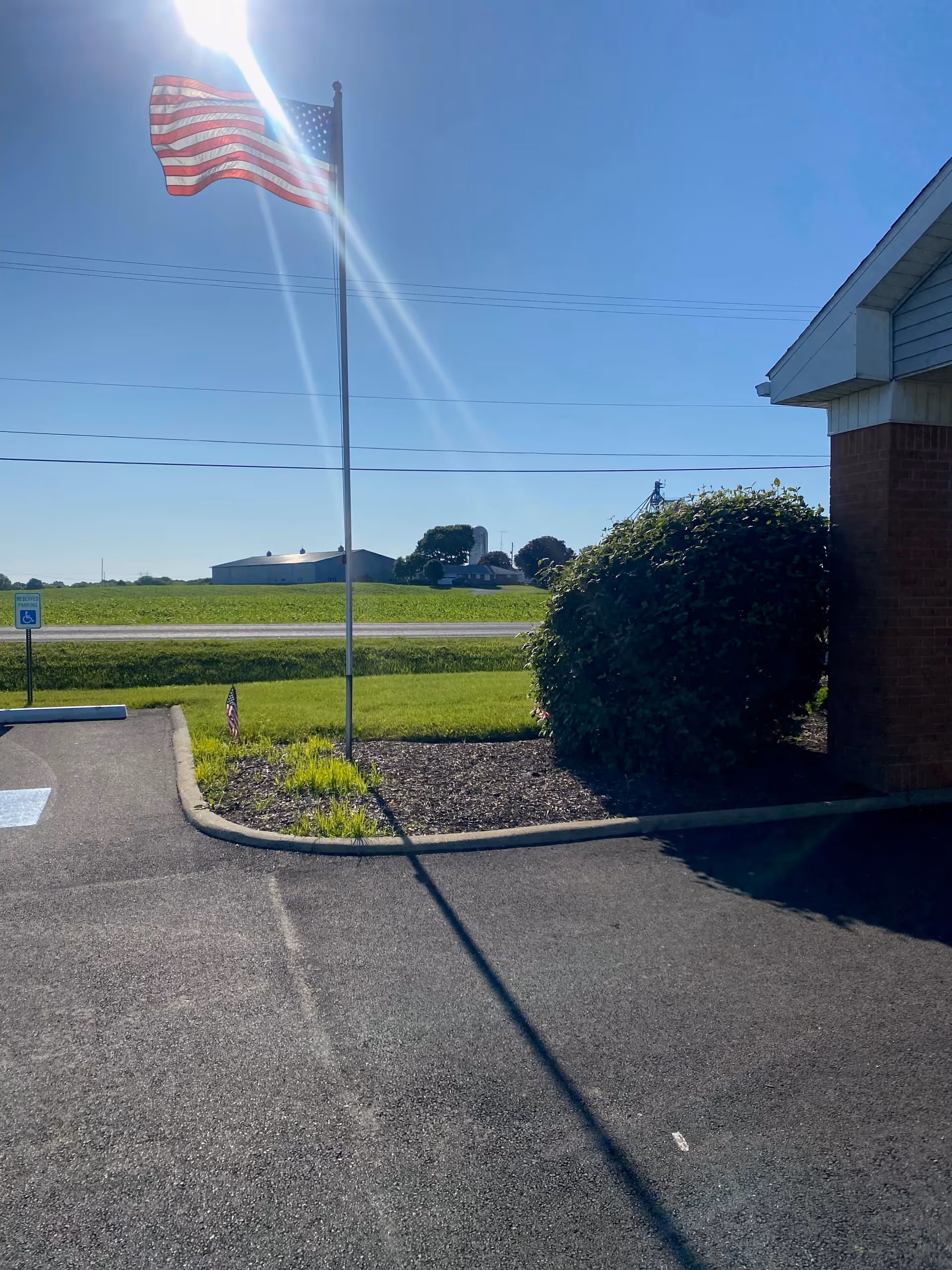 Exterior view of a flagpole, parking lot, and shrub near the building.