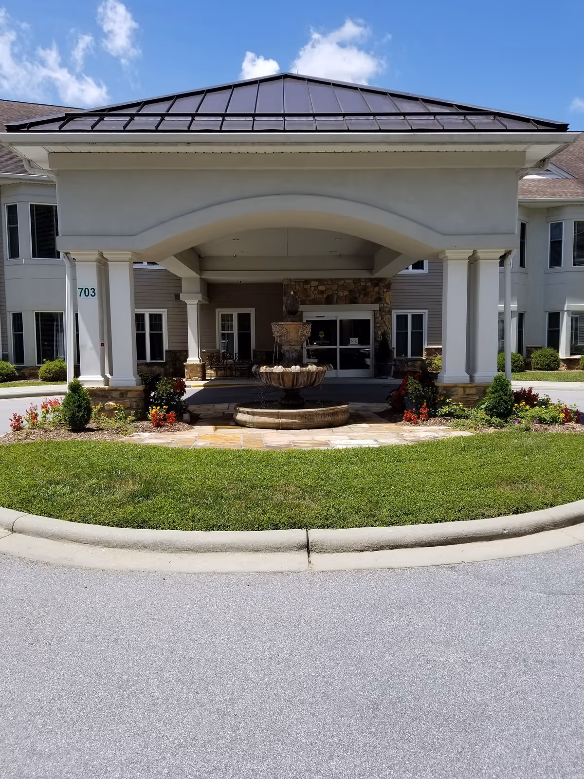 Exterior entrance of Carolina Village senior living with a central fountain and arches.