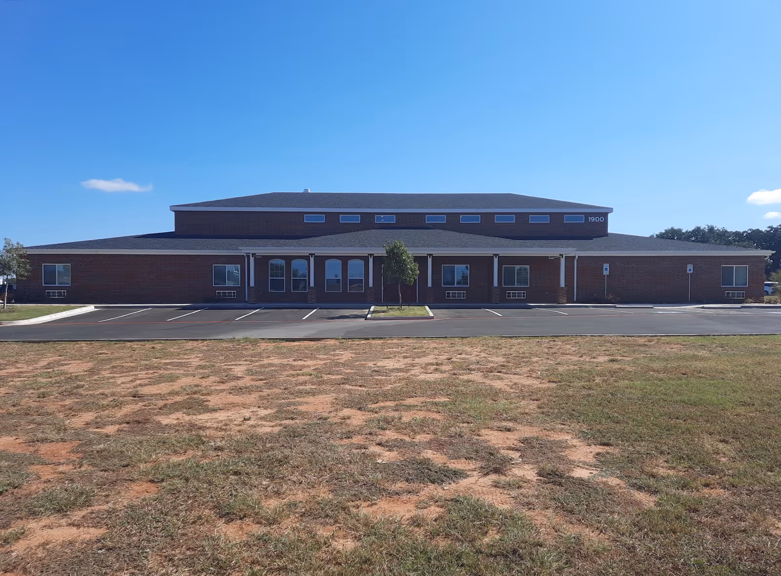 Brick senior living building with central front entrance and parking lot.