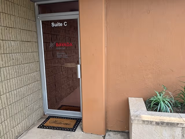 Exterior entrance to Suite C at BAYADA, with glass door and welcome mat.