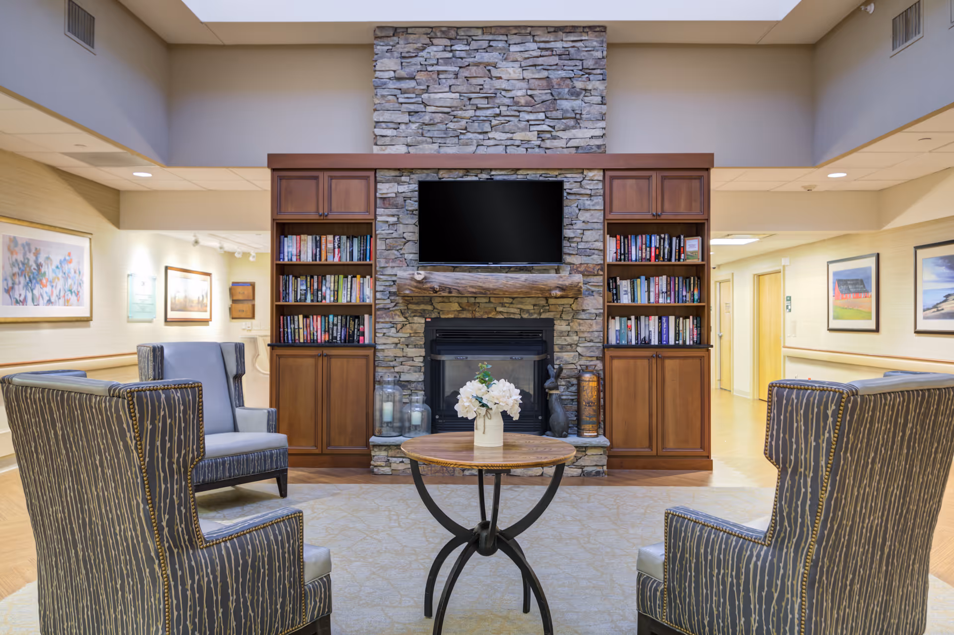 Cozy lobby seating around a stone fireplace with built-in bookshelves and a TV.