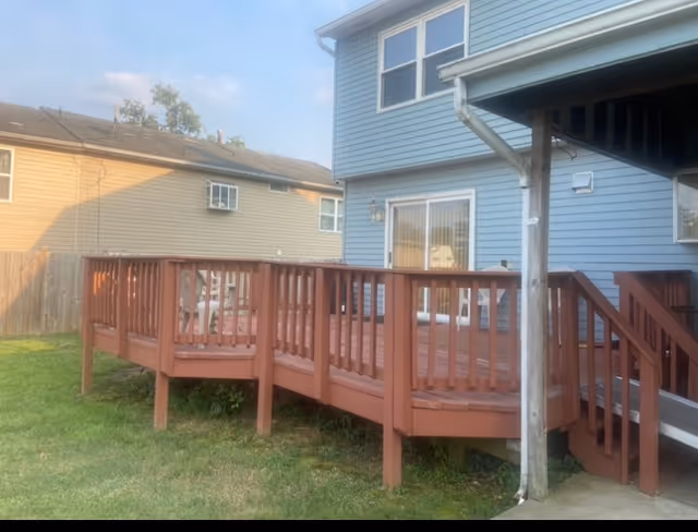 Blue two-story house with a wooden deck and green lawn in a suburban backyard.