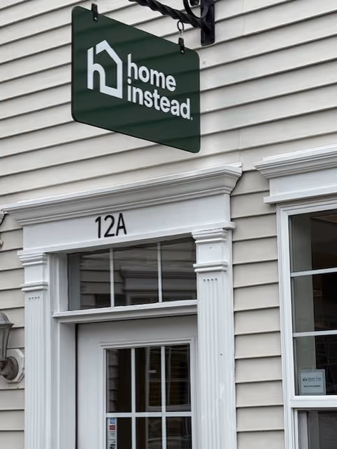 Exterior view of a Home Instead Guilford building with a hanging sign.
