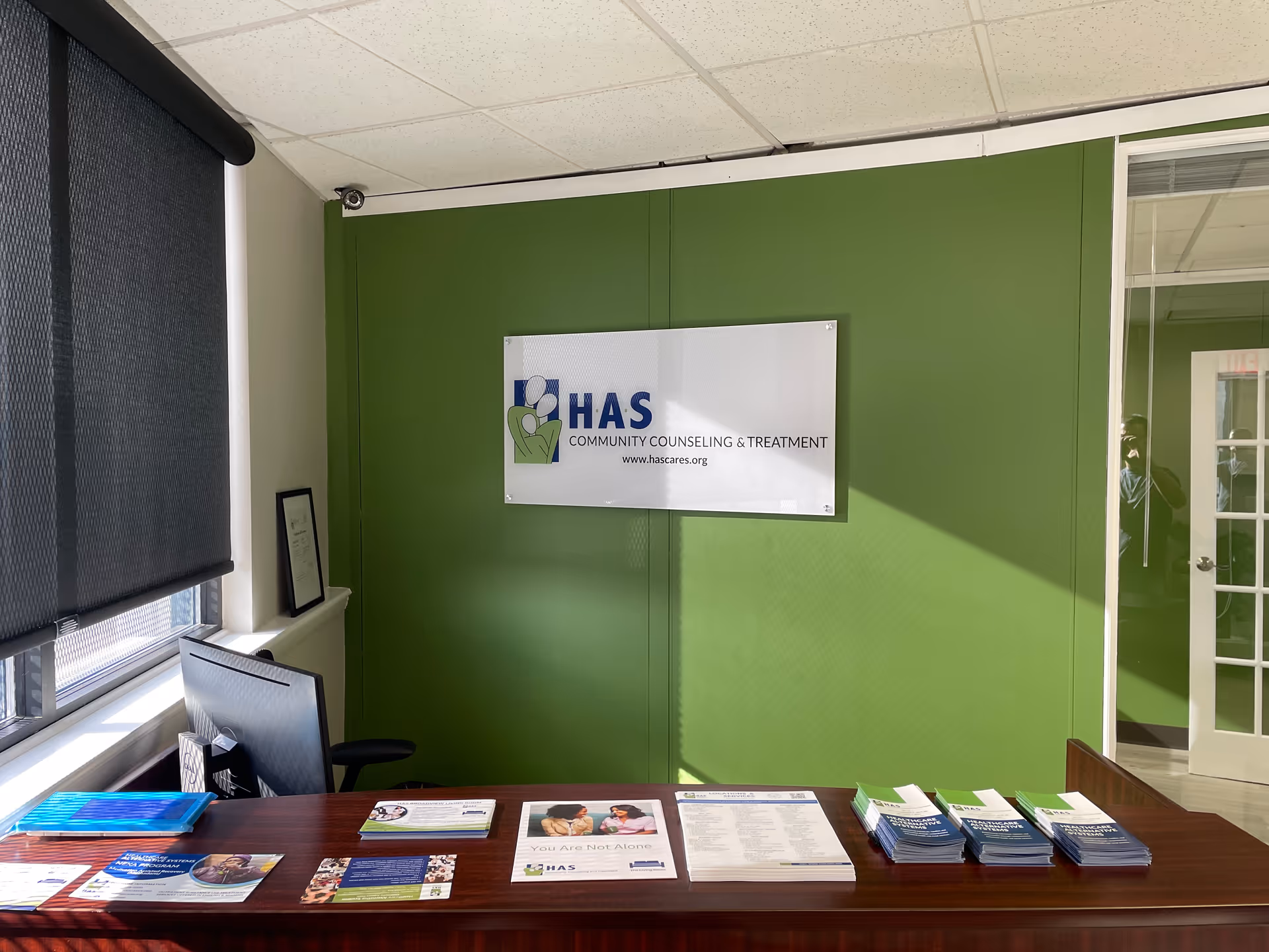 Interior reception area with a lime green wall, HAS sign, and brochures on a wood desk.