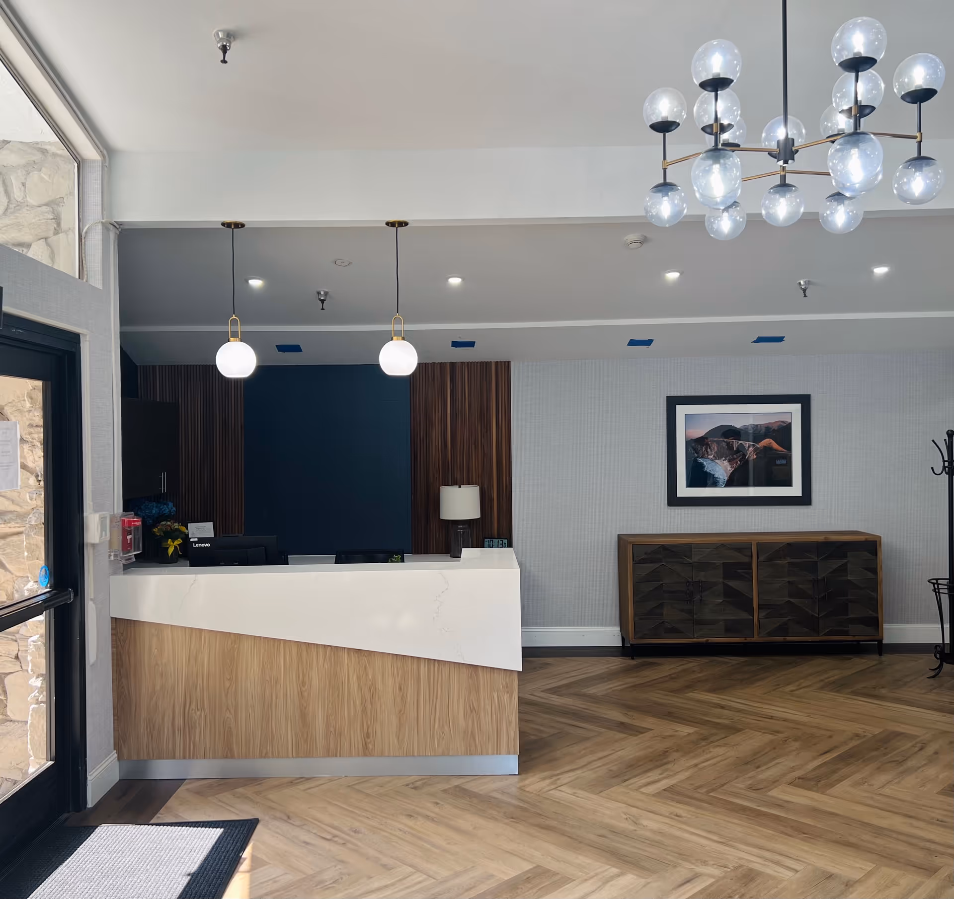 Modern lobby/reception area of Sunnyvale Post-Acute Center with wood desk and chandelier.