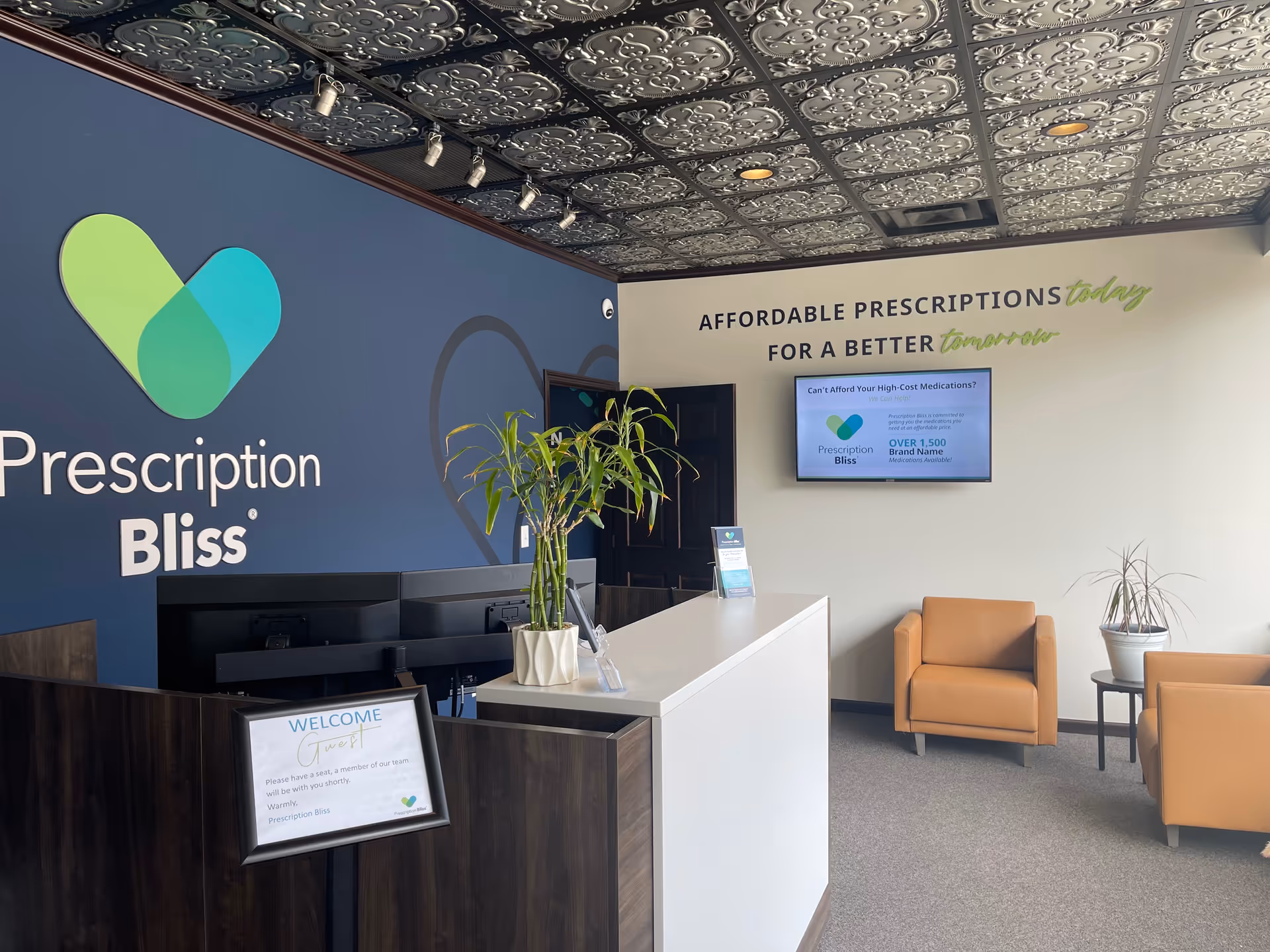 Reception area featuring Prescription Bliss branding on blue wall, with a white counter and chairs.