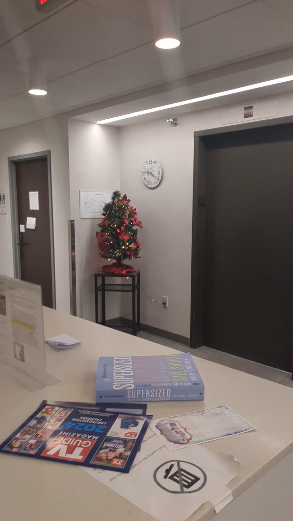Reception area of a senior living facility with a small Christmas tree near an elevator.