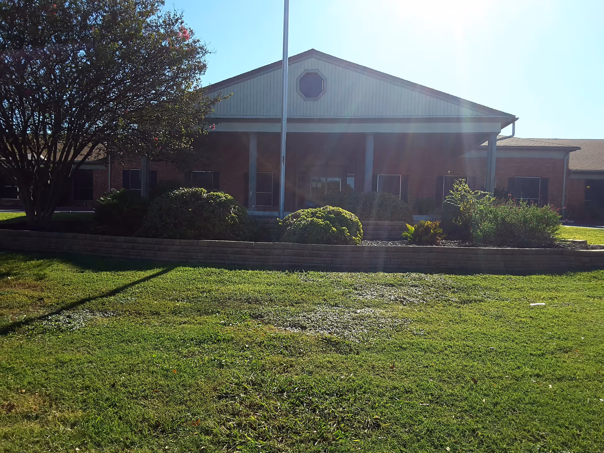 Exterior view of a brick senior living facility with a covered entrance and landscaped lawn.