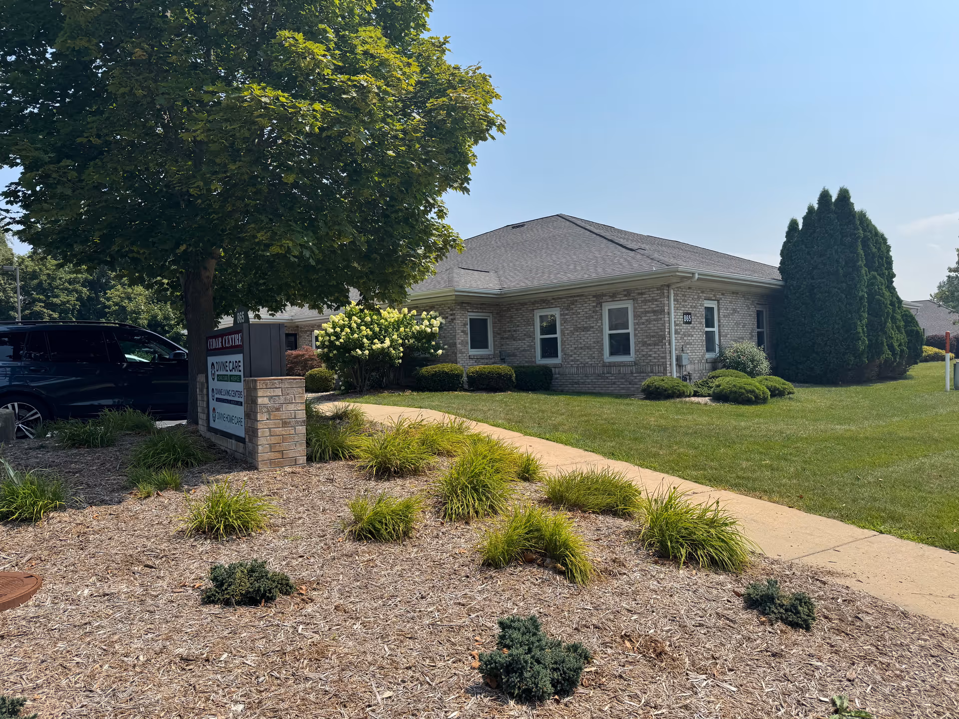 Brick facility building with manicured lawn and a sign reading Divine Care Home Health and Hospice.