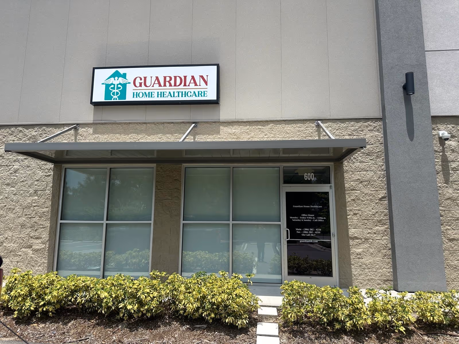 Front entrance of Guardian Home Healthcare building with sign and shrubs.