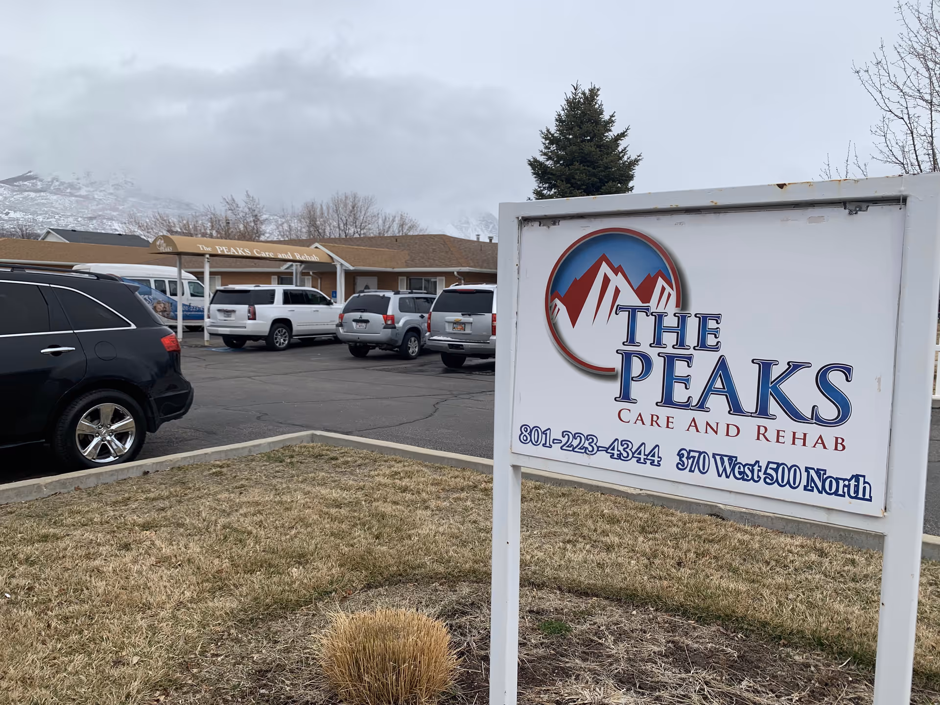 Parking lot in front of The Peaks Care and Rehab exterior with a sign.