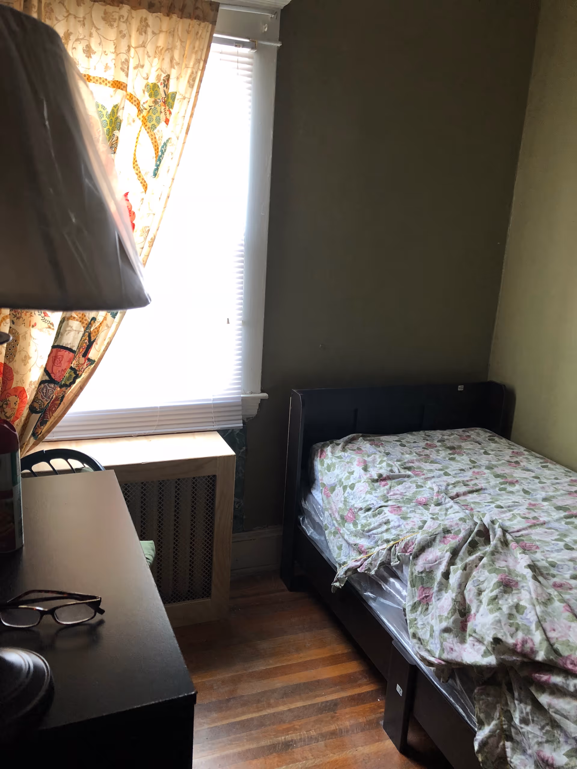 A small bedroom in a senior living facility with a single bed and floral bedding.