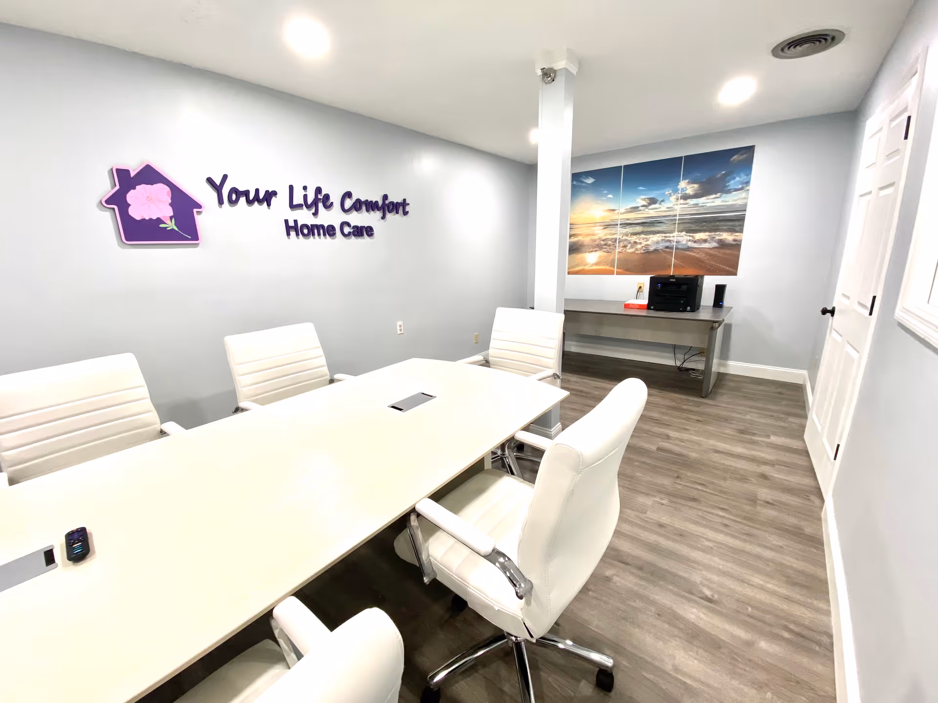 Conference room with a long white table, white chairs, and the facility logo on the wall.
