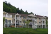Exterior view of a multi-story senior living building with balconies and green lawn.