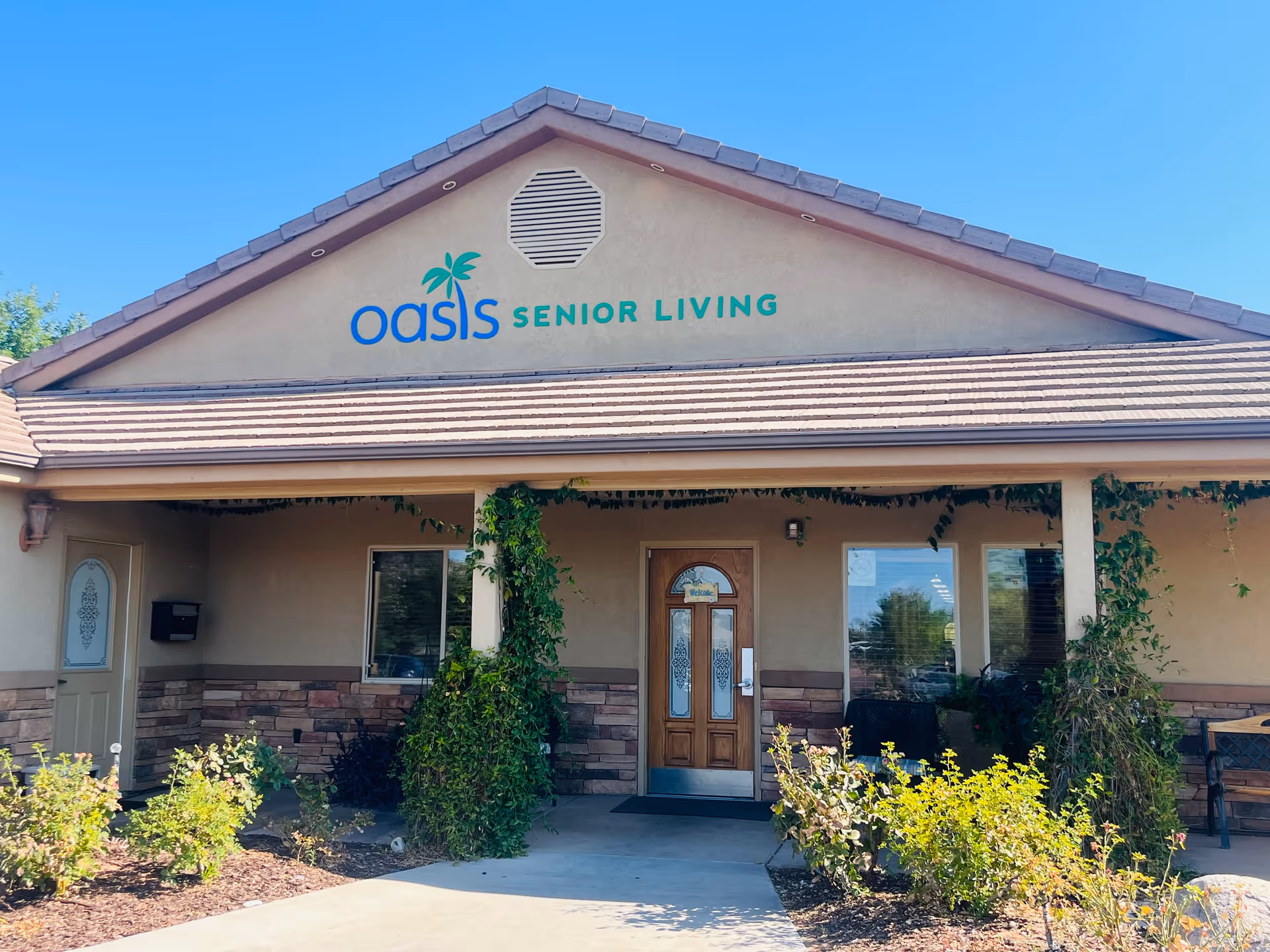 Exterior of a senior living facility with a wooden entrance door and climbing vines.