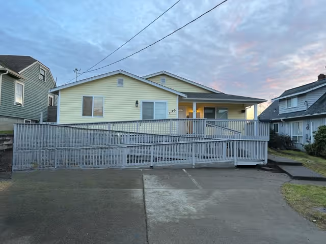 Front view of a yellow, single-story facility with a long ramp and railings.