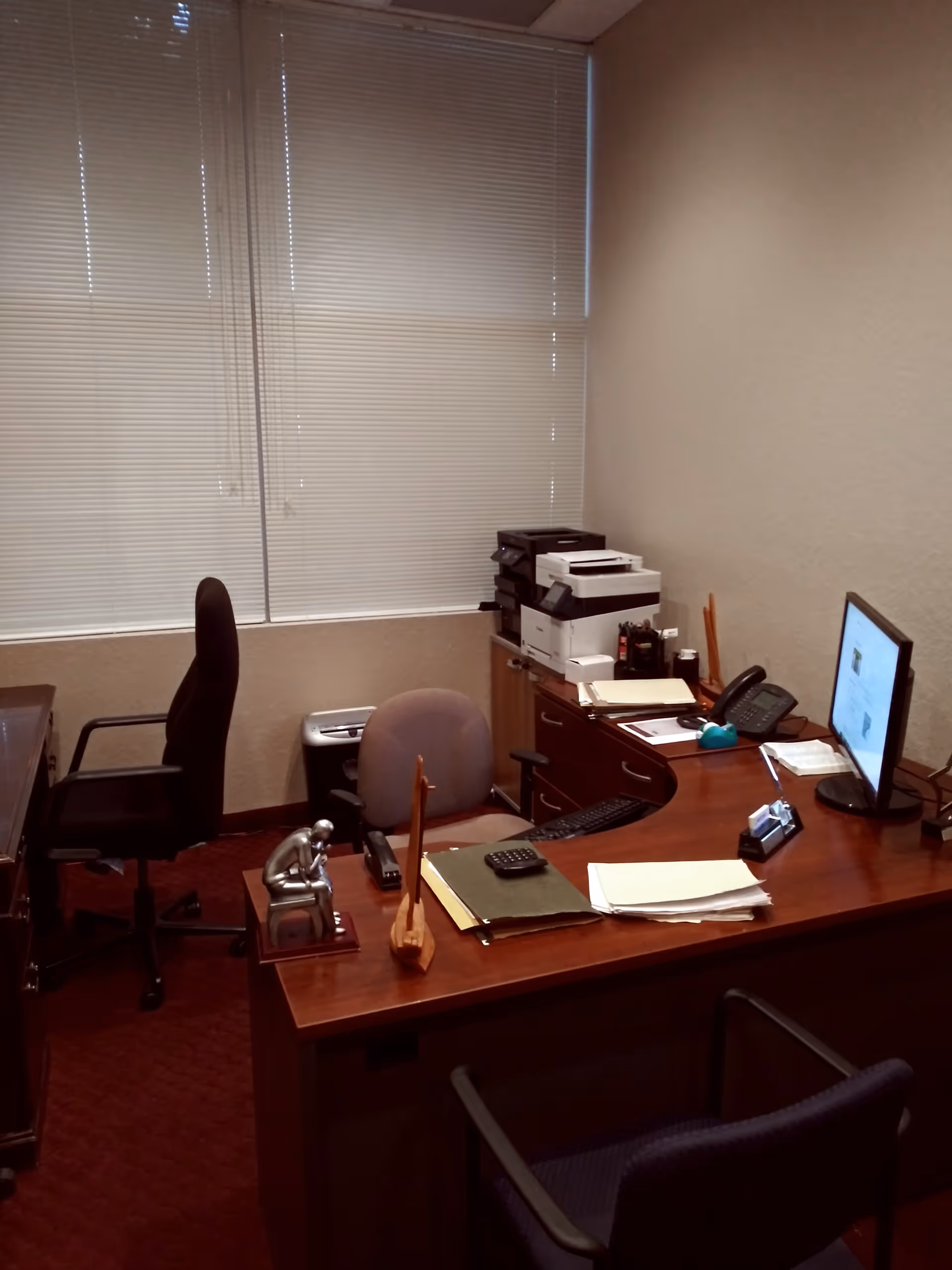 Interior office workspace in a senior living facility with a wooden desk, computer, and printer.