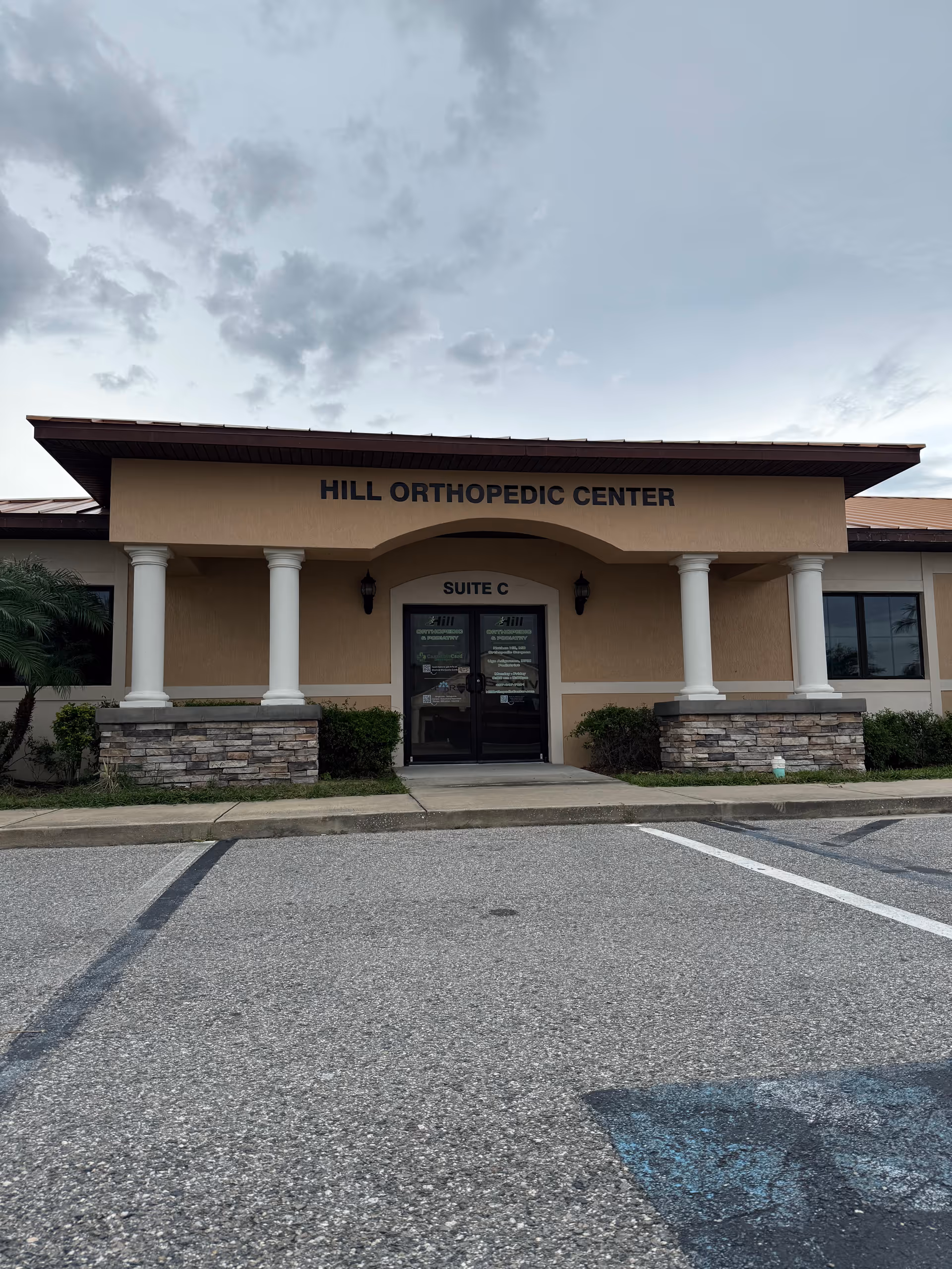 Front exterior of a beige medical building labeled Hill Orthopedic Center with columns and double doors.