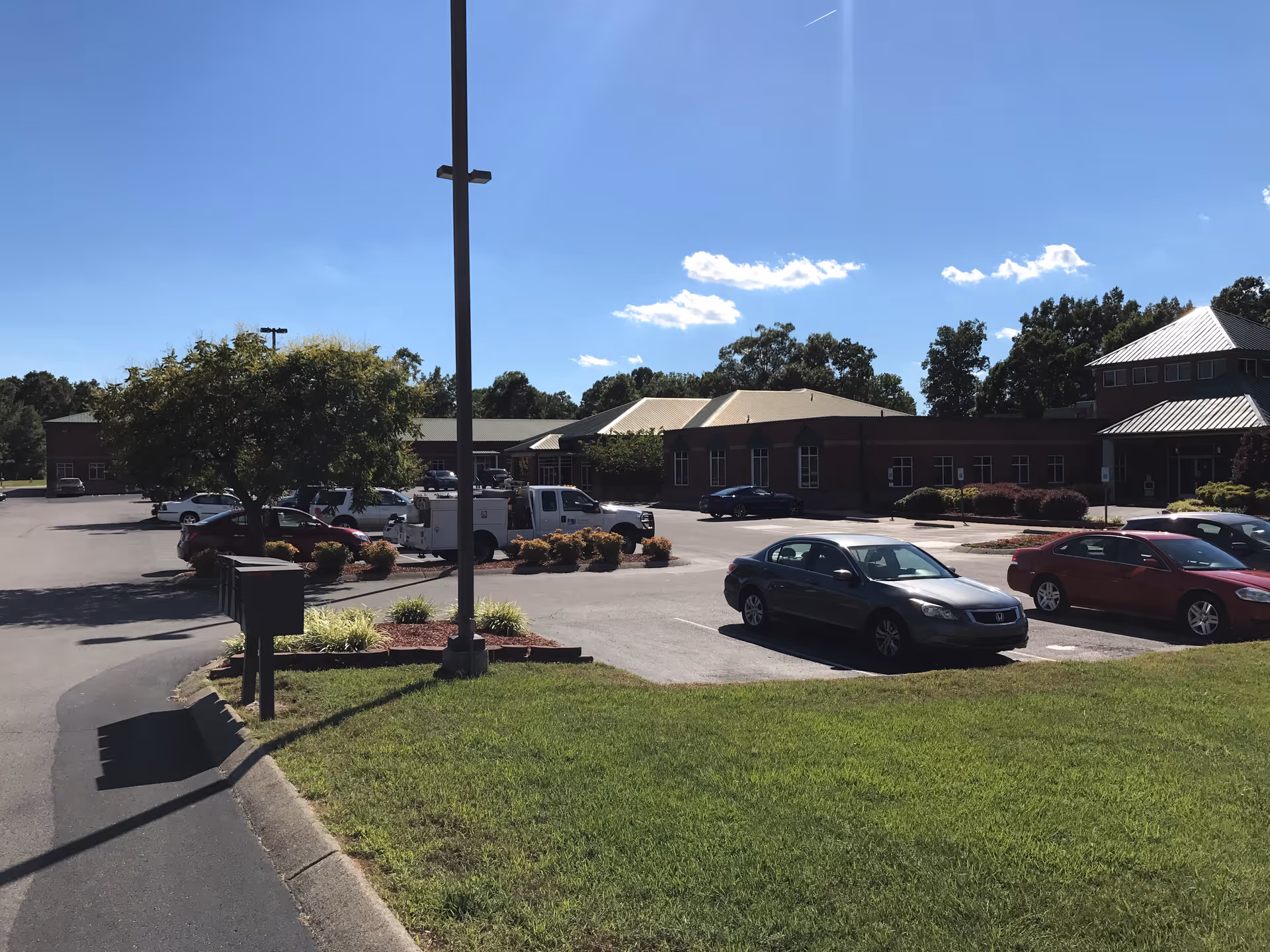 Exterior view of a senior living facility with parked cars and landscaping.