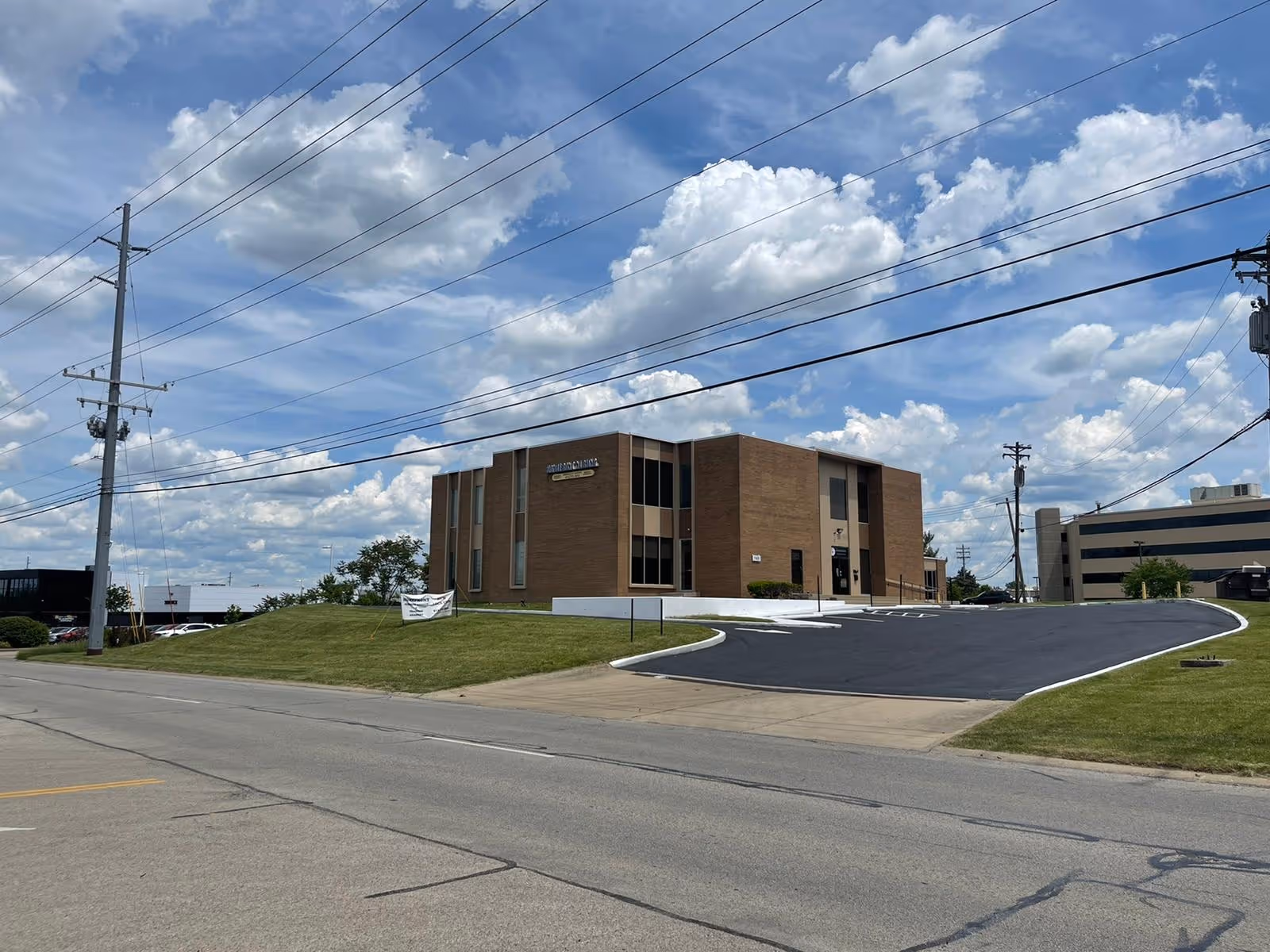 Exterior view of Homefront Nursing brick building with a curved driveway under a blue sky.