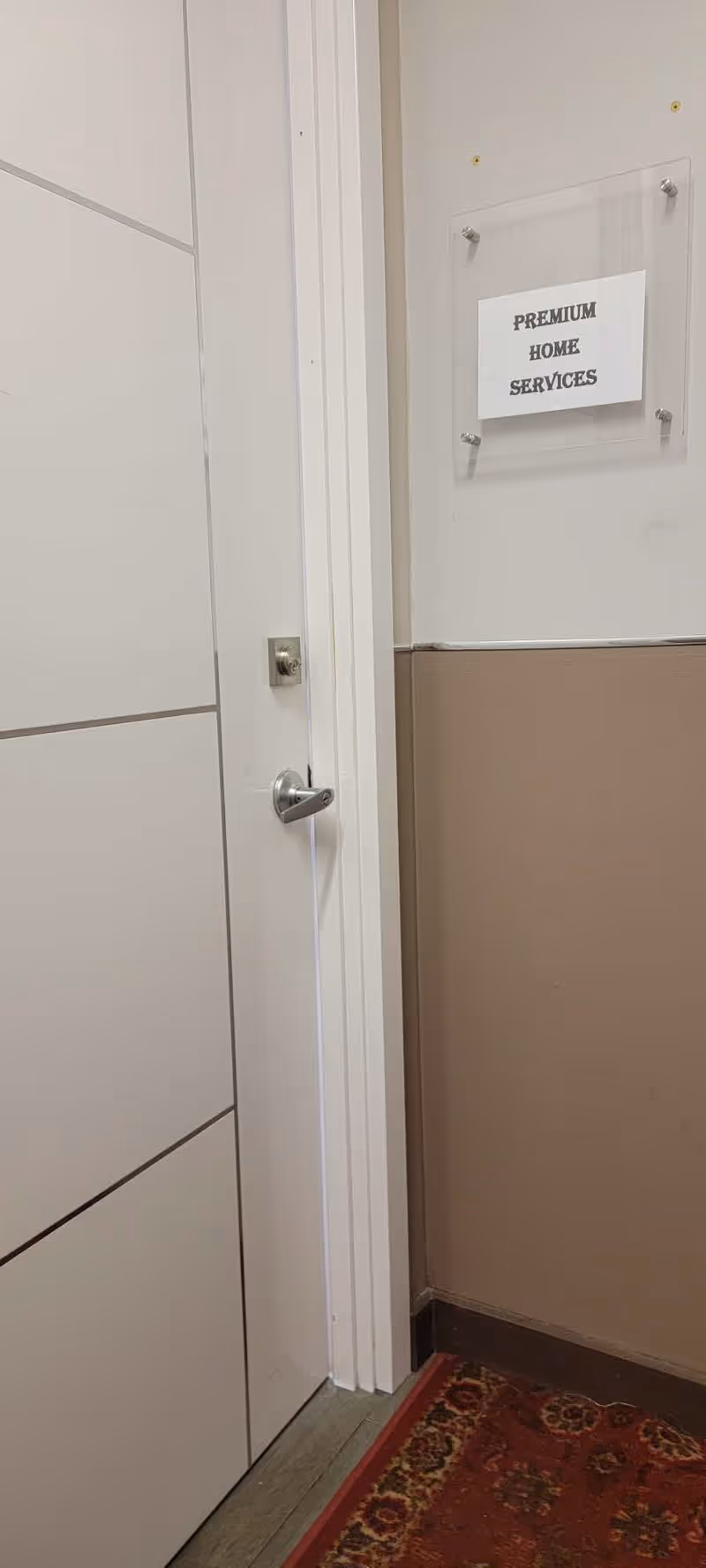 White interior hallway with a door and a plaque reading Premium Home Services.