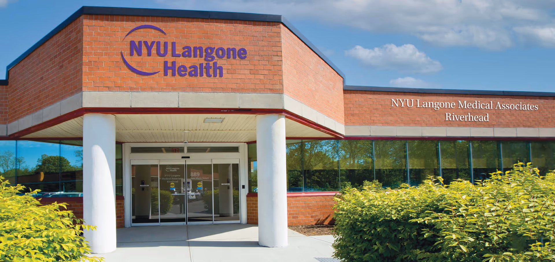 Front view of NYU Langone Medical Associates Riverhead building entrance with glass doors