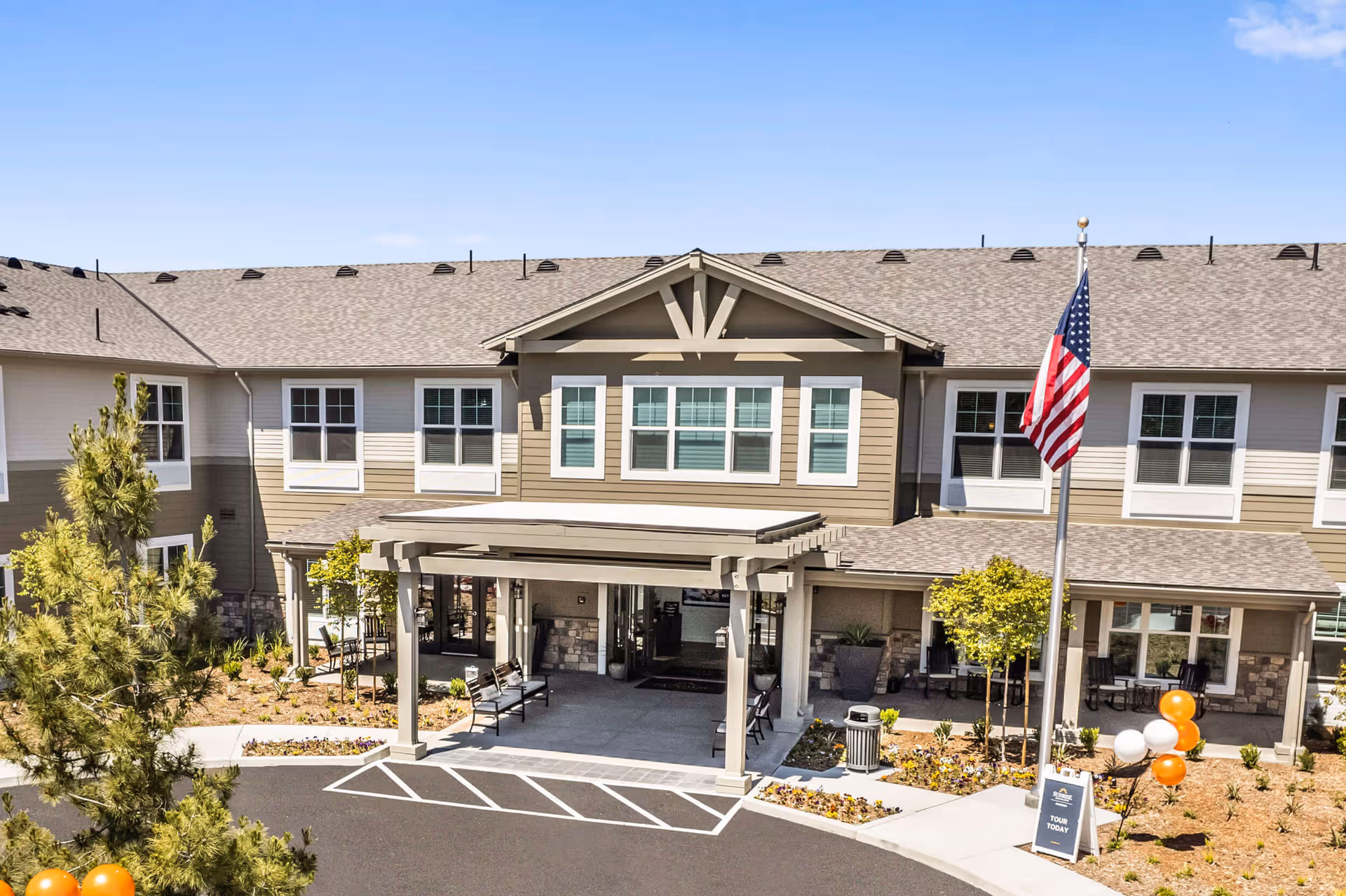 Sunrise of Oceanside facility façade with entrance canopy, American flag, and landscaping.