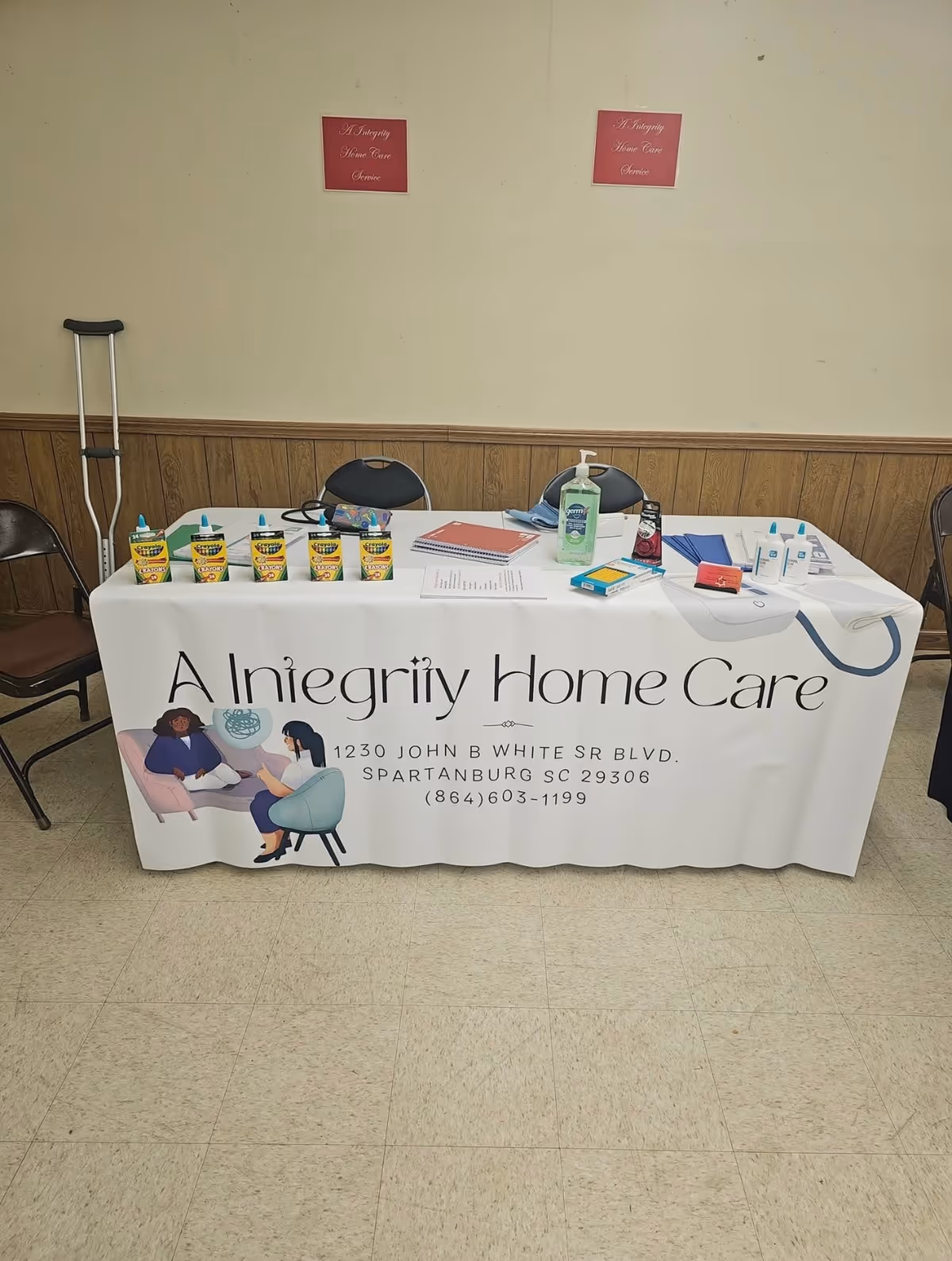 Branded display table for A Integrity Home Care in a plain interior room.