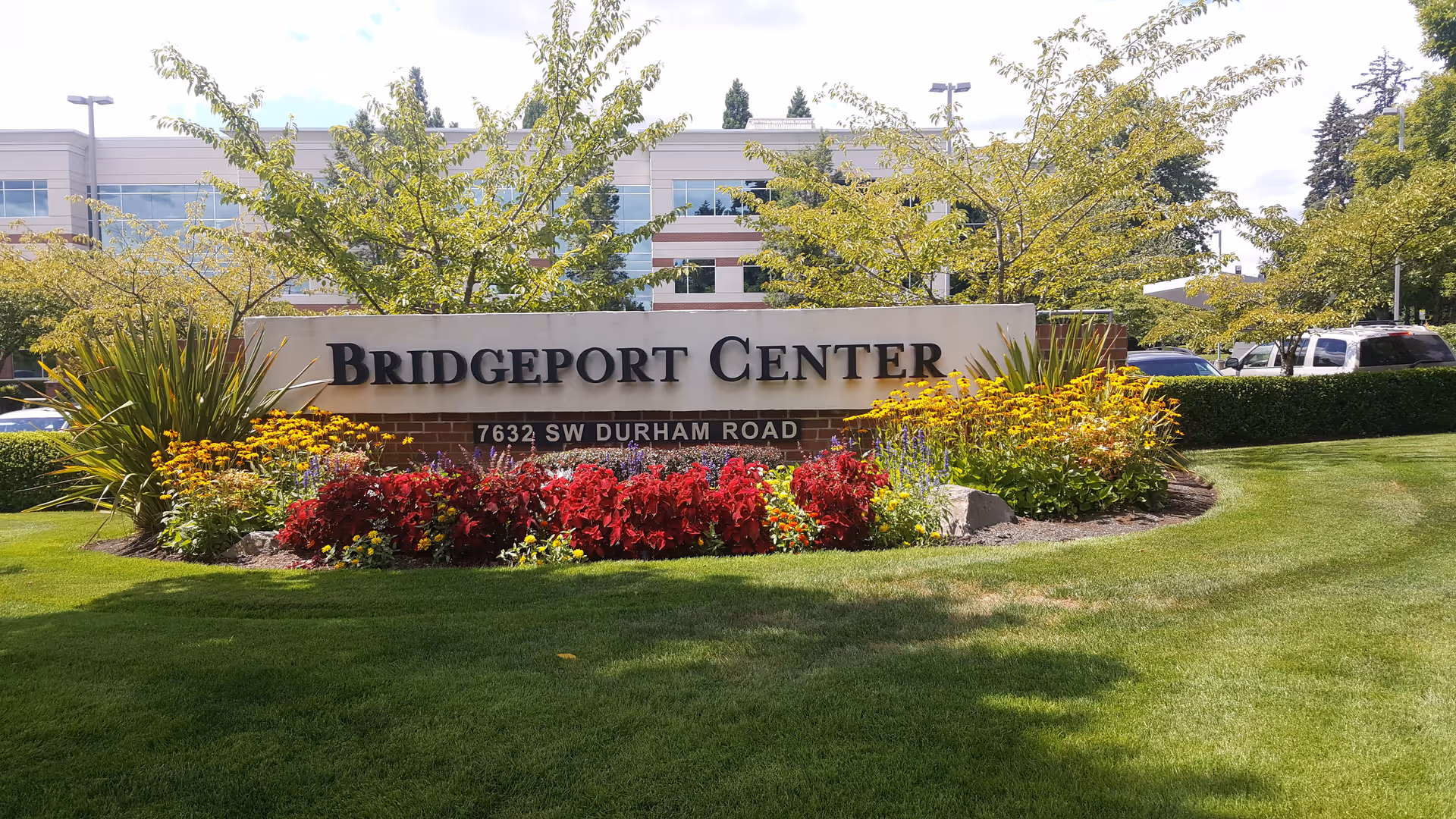 Bridgeport Center sign with colorful flowers and green lawn in front of a building